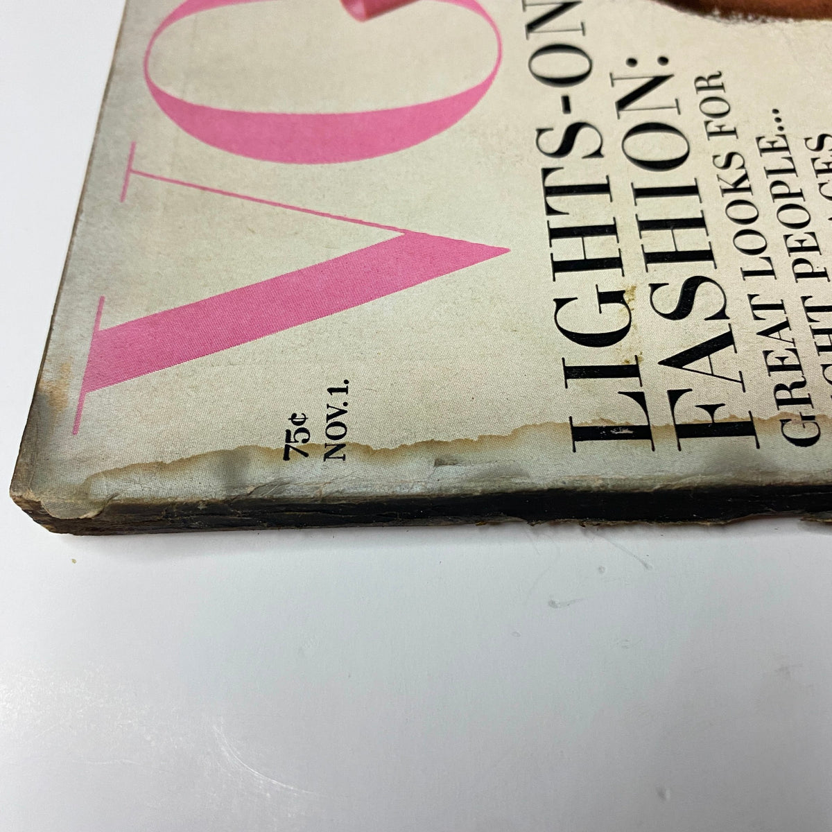 Close-up of the corner of a Vogue Magazine from November 1, 1965. The image shows wear and aging on the magazine's spine, with the title clearly visible as 'Vogue' and the issue date prominently displayed.