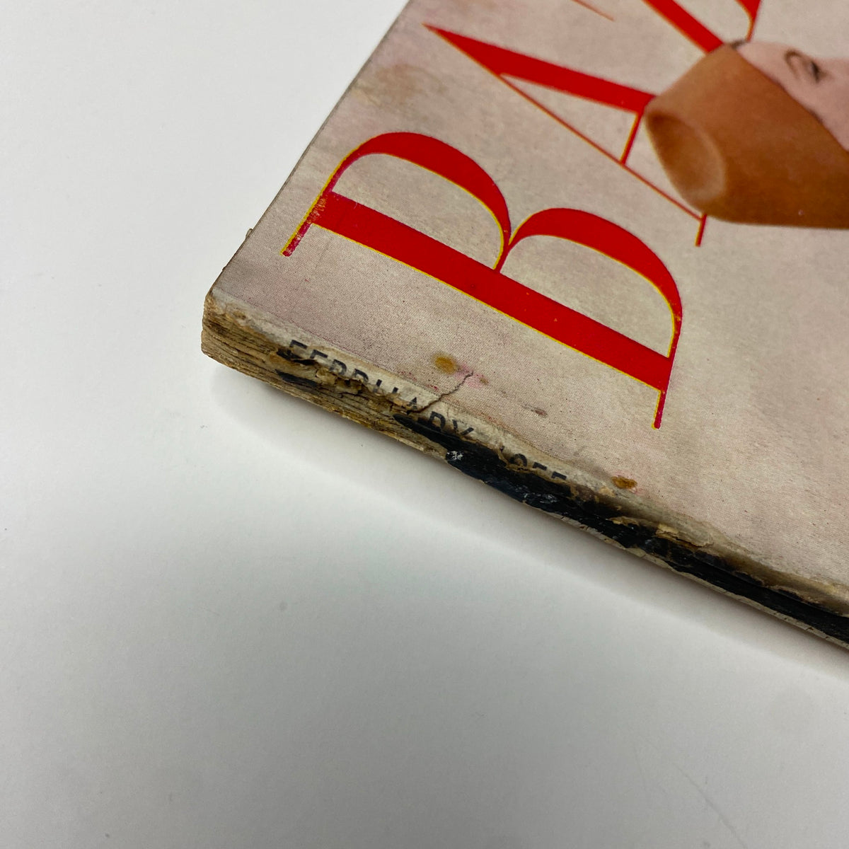 Close-up of the spine of Harper's Bazaar Magazine February 1955, showing signs of wear and the month and year 'February 1955' clearly visible.