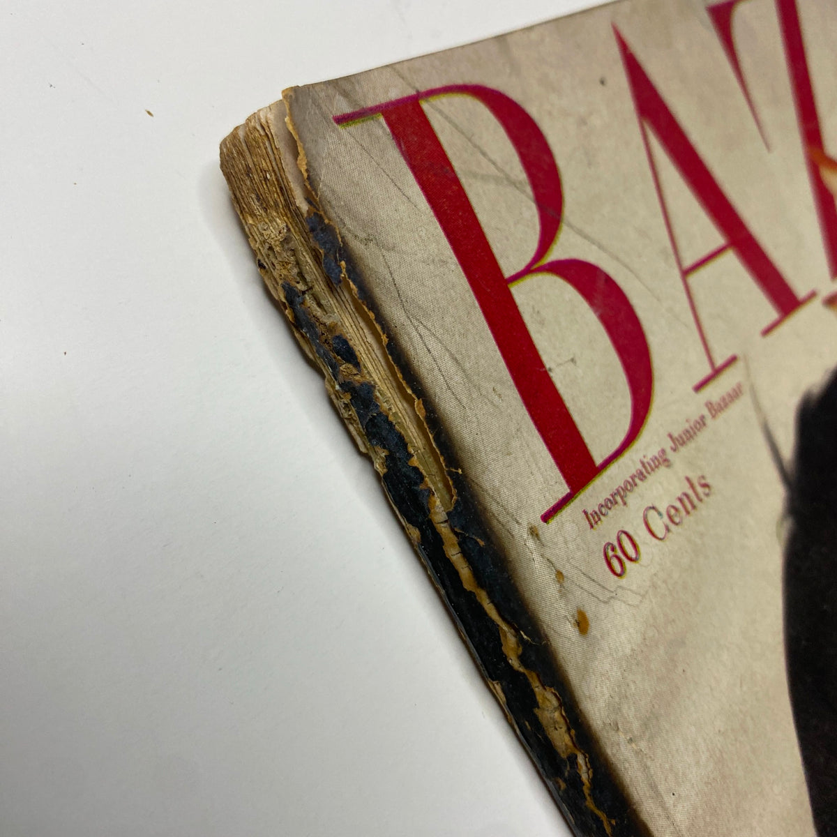 Edge detail of Harper's Bazaar Magazine December 1955, showing wear and age with a faded cover associated with Evelyn Tripp's image by Louise Dahl-Wolfe.
