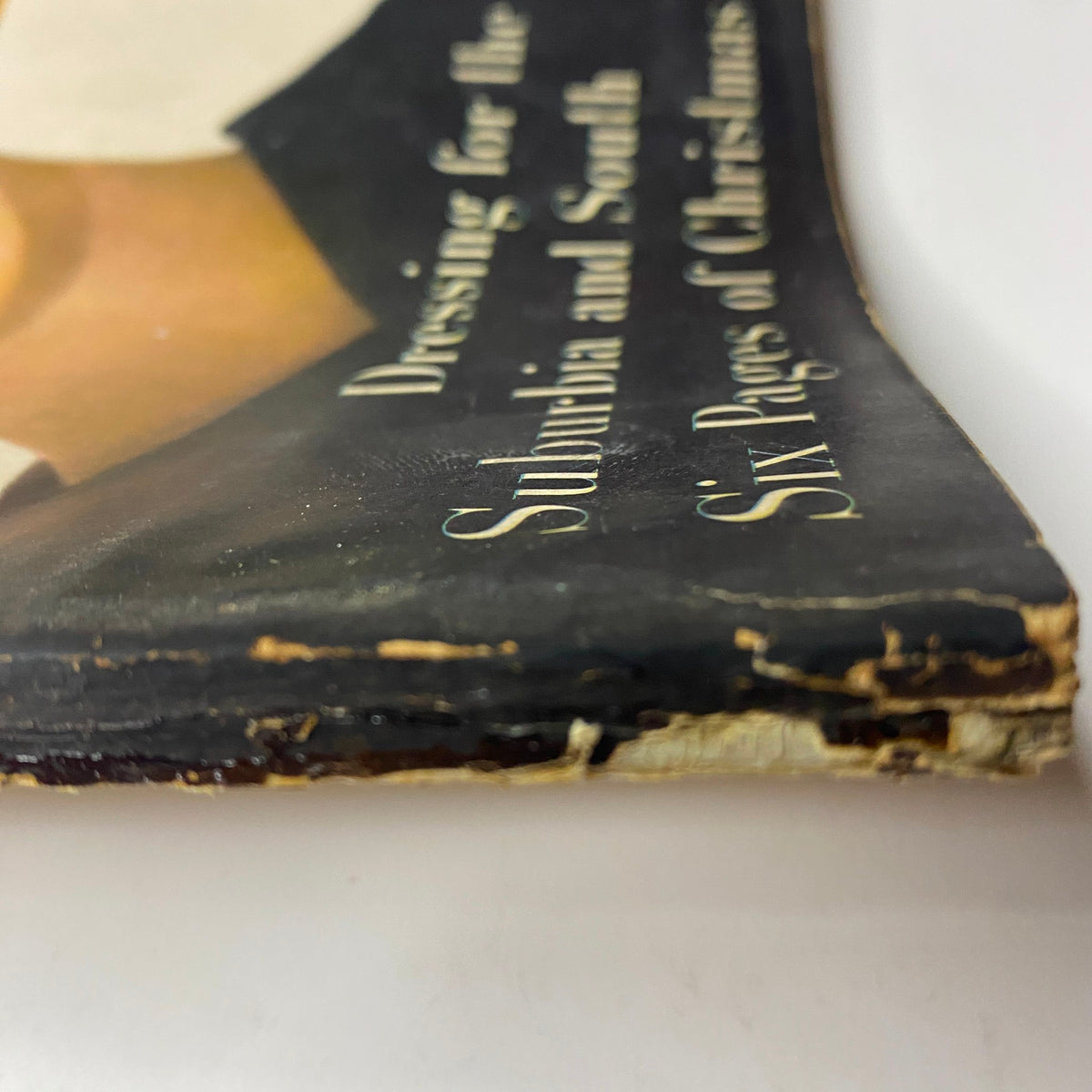 Spine view of Harper's Bazaar Magazine December 1955, displaying wear, emphasizing the vintage nature of the issue featuring Evelyn Tripp.