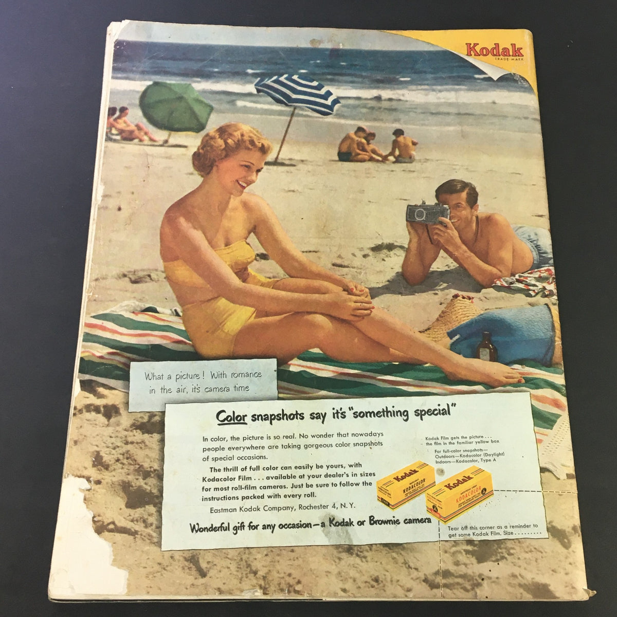 Vintage Kodak advertisement from The Saturday Evening Post, June 10, 1950 showcasing a beach scene with a woman in a swimsuit and a man taking a photo, promoting Kodak cameras.