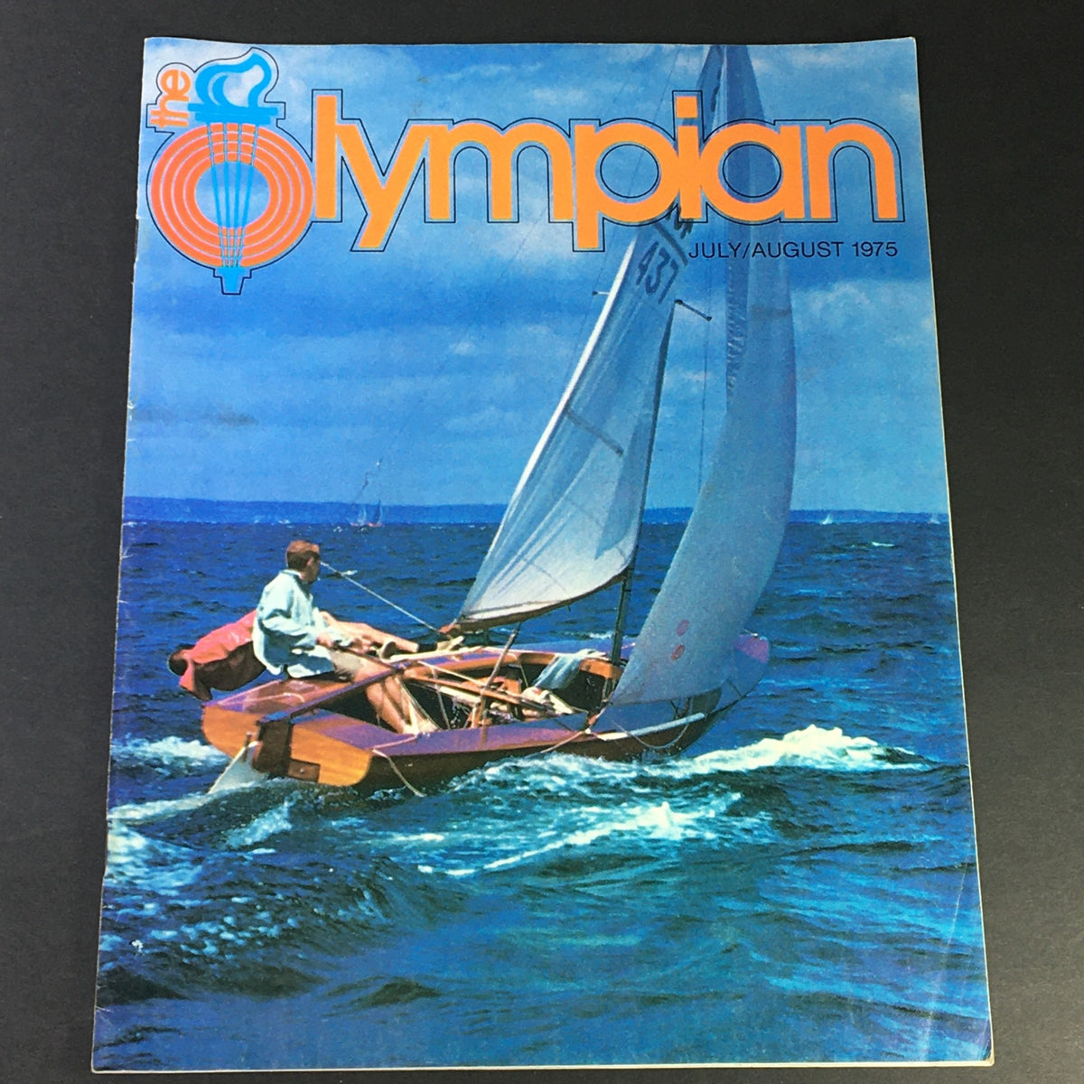 Cover of VTG The Olympian Magazine July August 1975 Vol 2 #1, featuring a person sailing in an Olympic-class boat on the water.