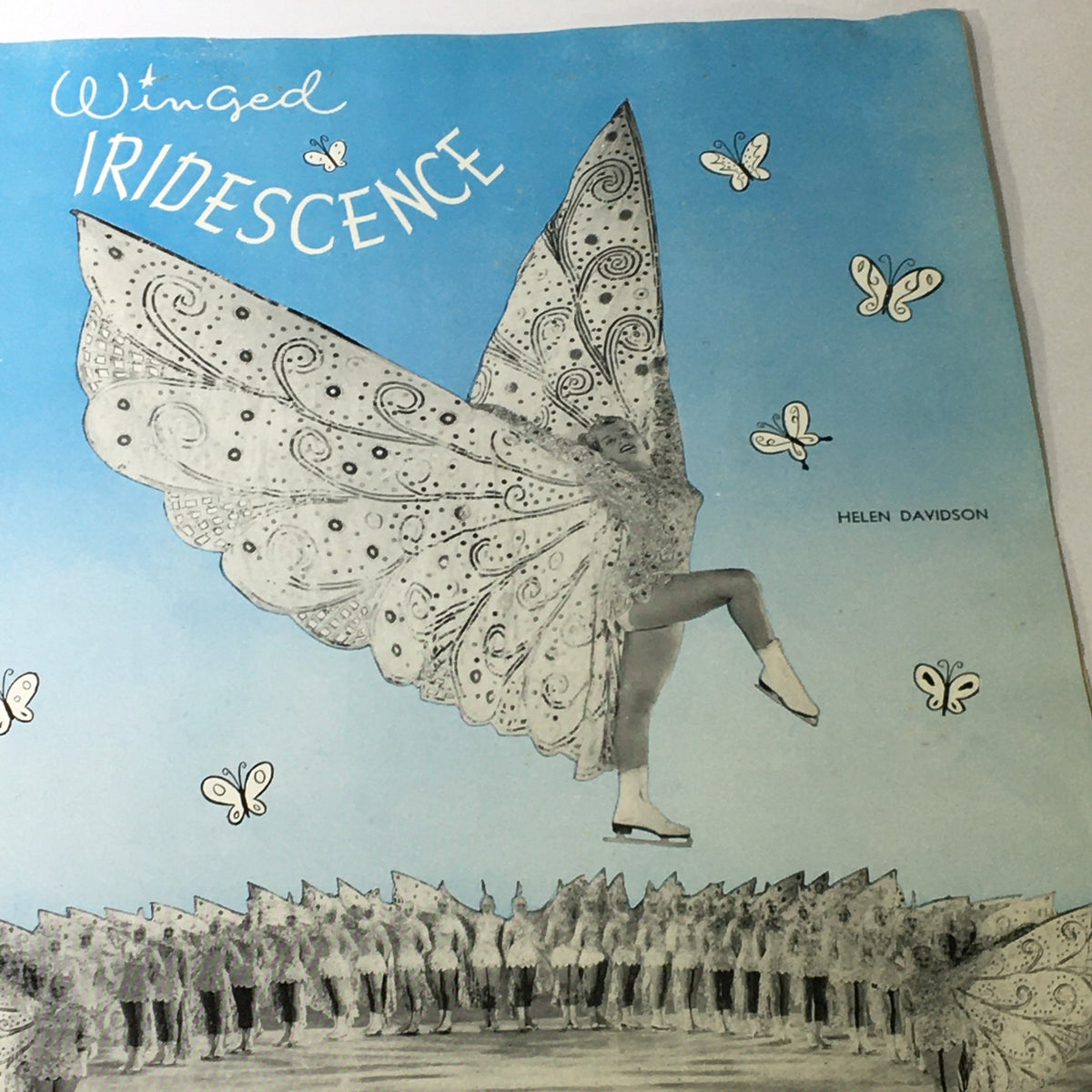 Illustration from the VTG Ice Capades Brochure of 1950 titled 'Winged Iridescence', featuring a dancer adorned with large butterfly wings against a light blue background.