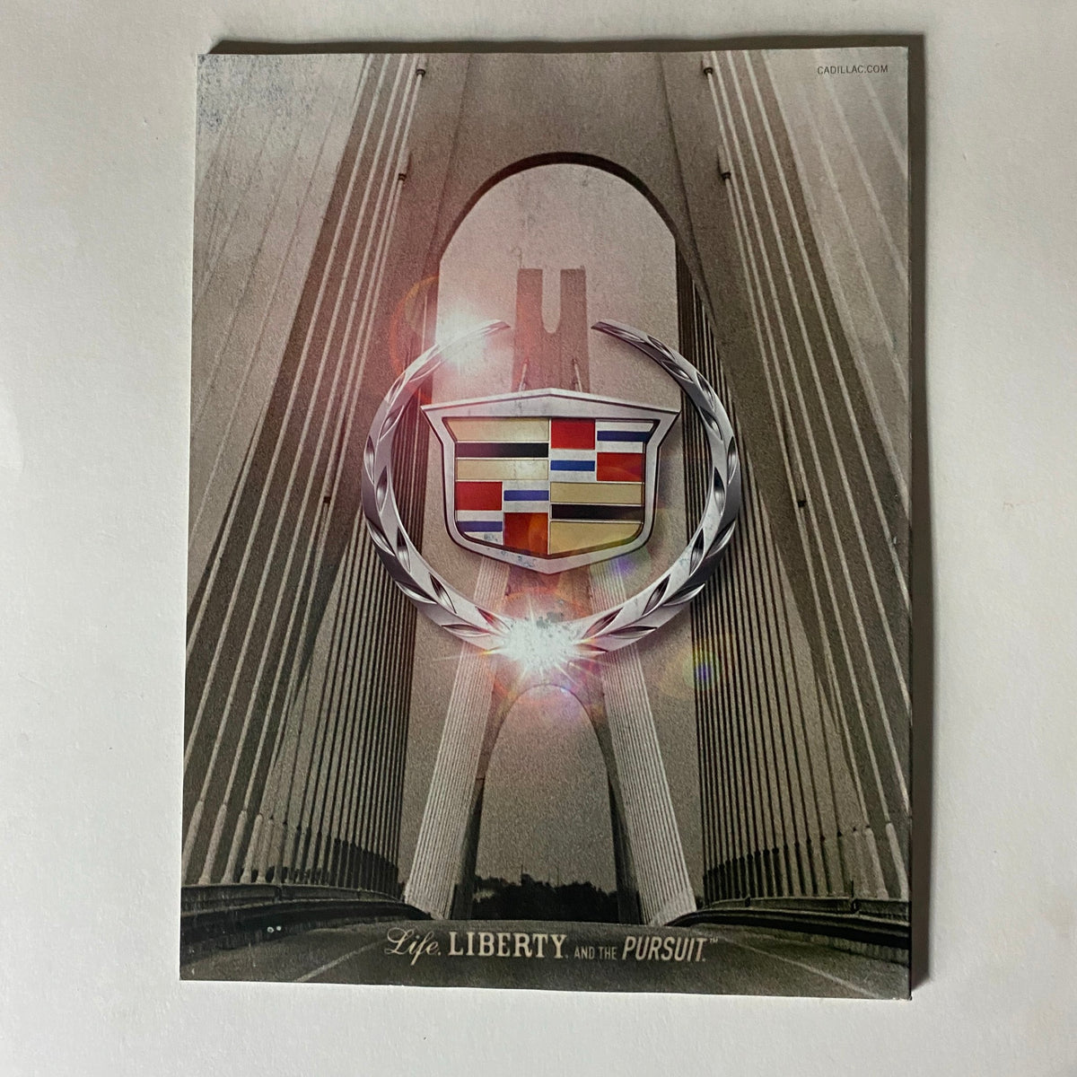 Promotional image of a Cadillac featuring the caption 'Life, Liberty, and the Pursuit,' set against an artistic background of a bridge, included in Fortune Magazine August 7, 2006.