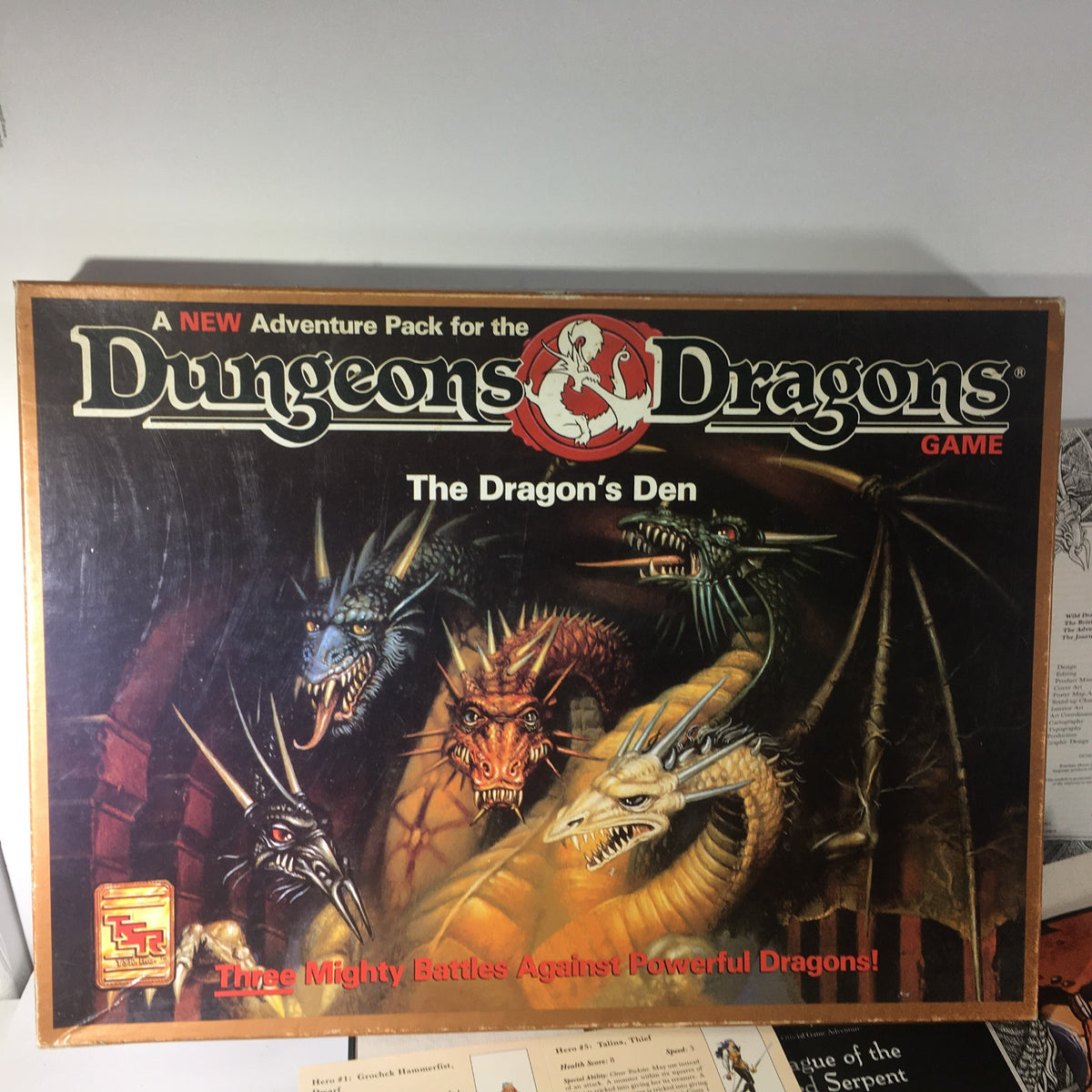 Box cover of TSR Board Game: Dungeons & Dragons Game The Dragon's Den, showcasing dragons and adventure themes.