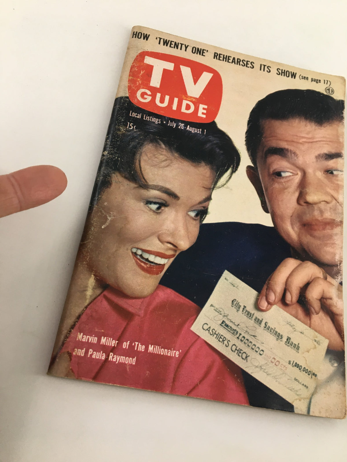 Close-up view of TV Guide Magazine July 26 1958, highlighting Marvin Miller and Paula Raymond, with a focus on the magazine's vintage design and details like the cashier's check.