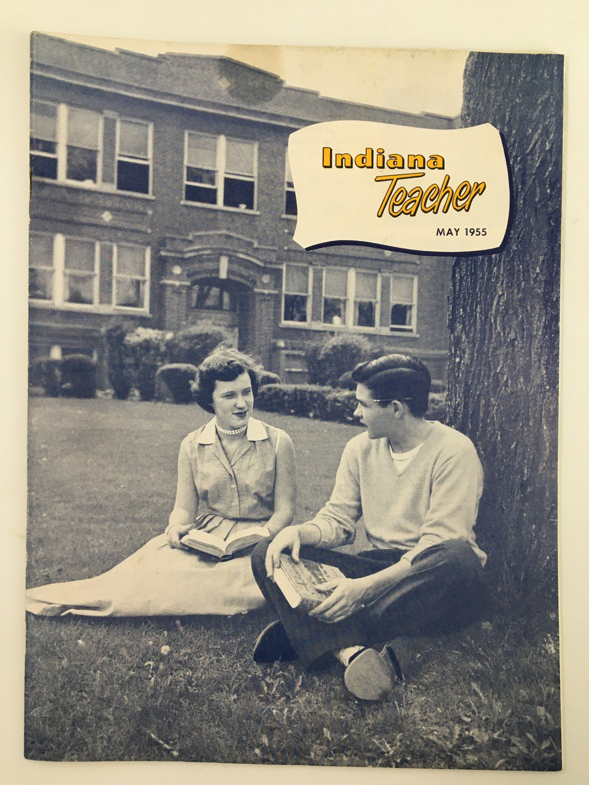 VTG Indiana Teacher Magazine May 1955 cover featuring a scene with two students sitting on the grass in front of a school building, discussing educational topics.