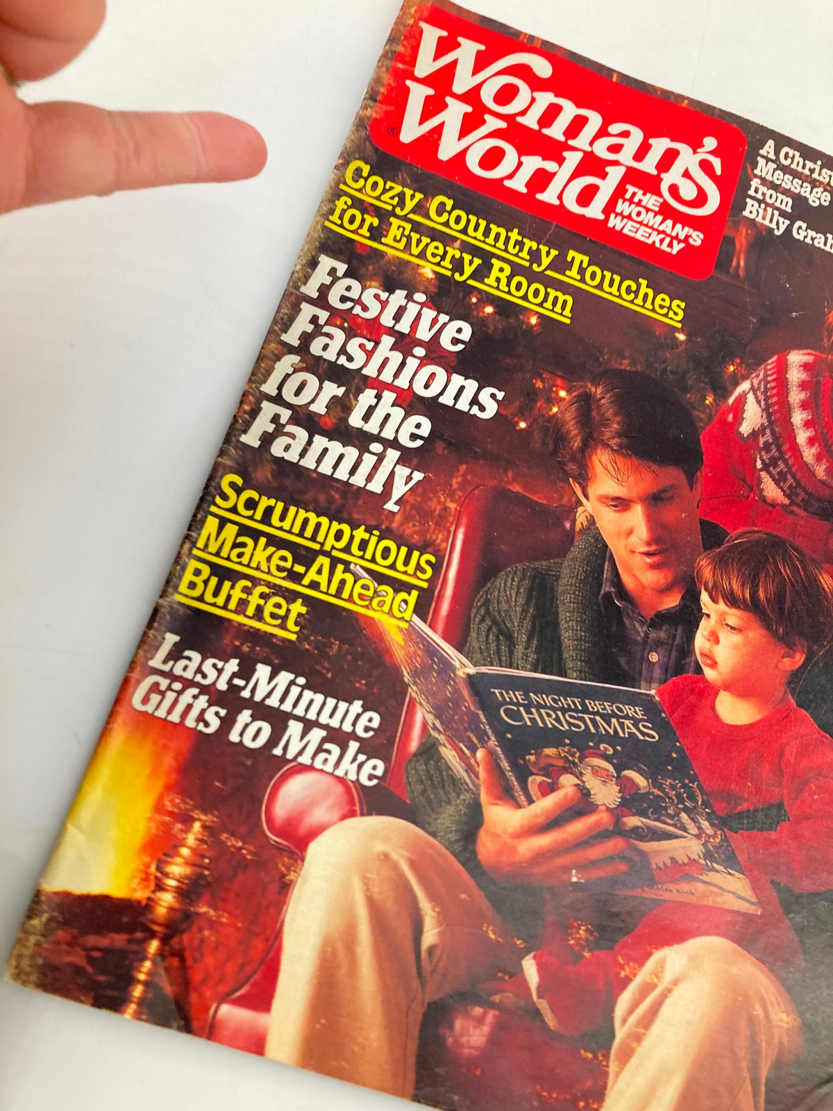 Close-up of Woman's World Magazine December 23 1986 cover showing cozy family reading 'The Night Before Christmas' by the fireplace, promoting family togetherness and Holiday spirit.
