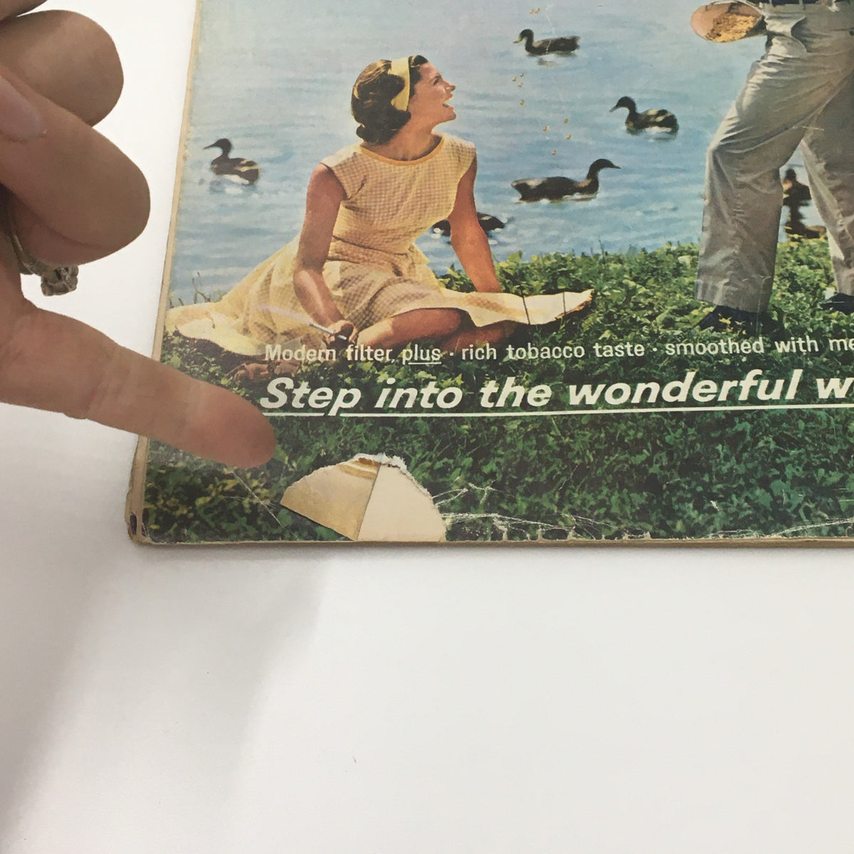 Close-up of VTG Life Magazine July 10, 1964 that shows a woman in a yellow dress and a hand pointing to an advertisement on the cover, highlighting the product Salem Cigarettes.