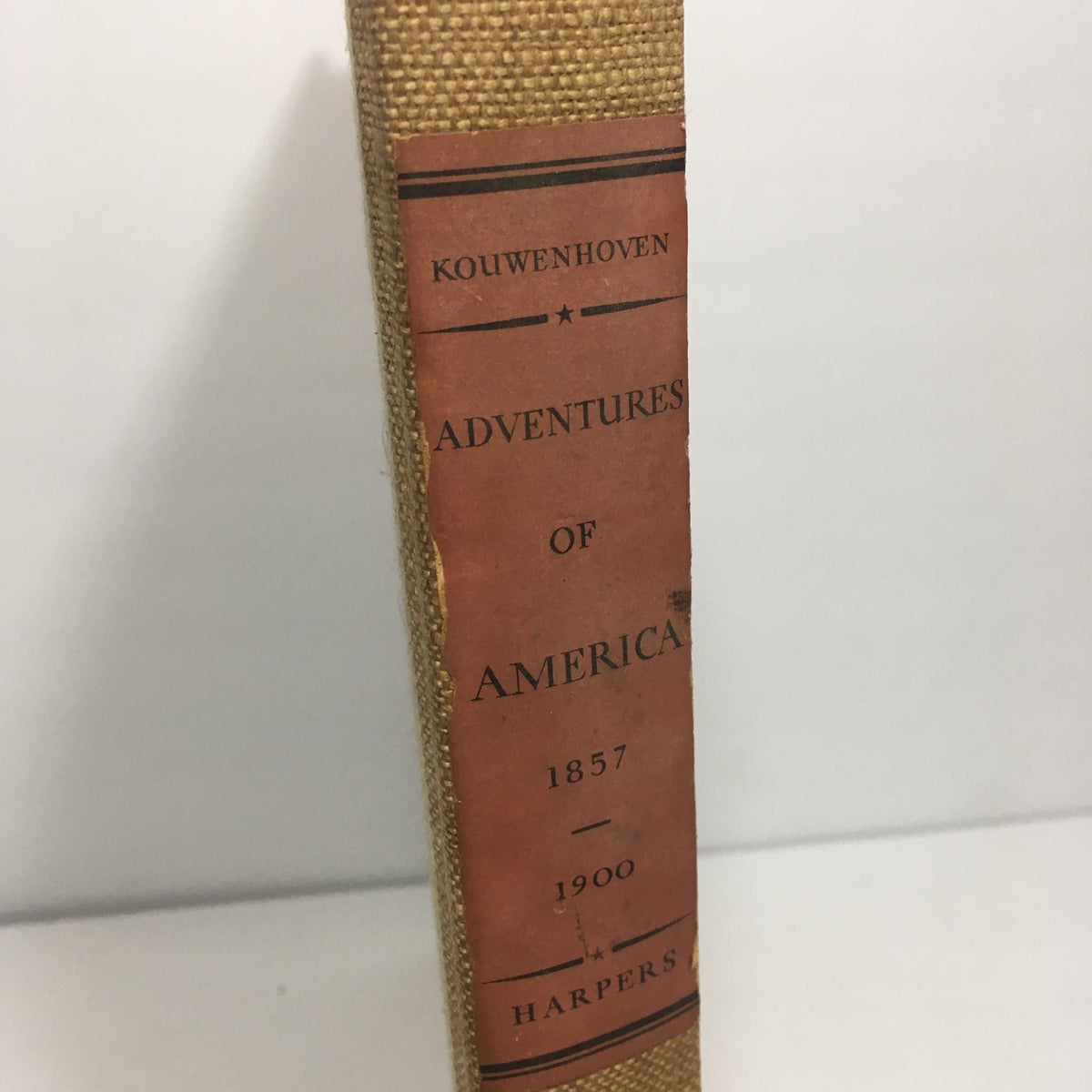 Close-up of the spine of 'Adventures of America 1857 - 1900' by John Kouwenhoven, highlighting the author's name and publication year.