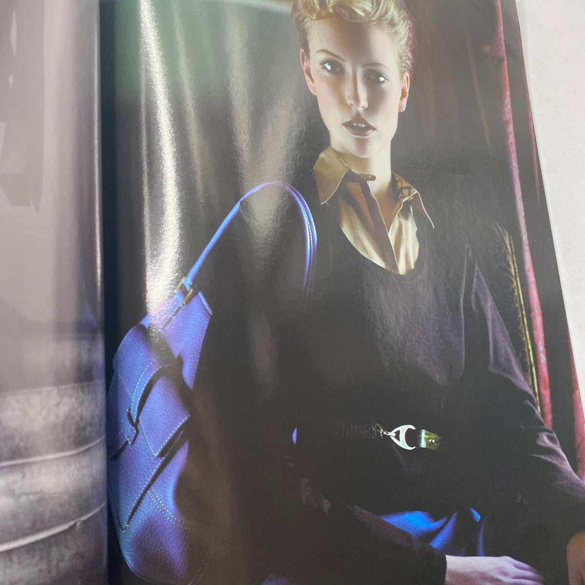 Fashion photograph from Harpers Business Magazine October 2005, featuring a model with a chic outfit and a bold blue handbag, illustrating contemporary business fashion.