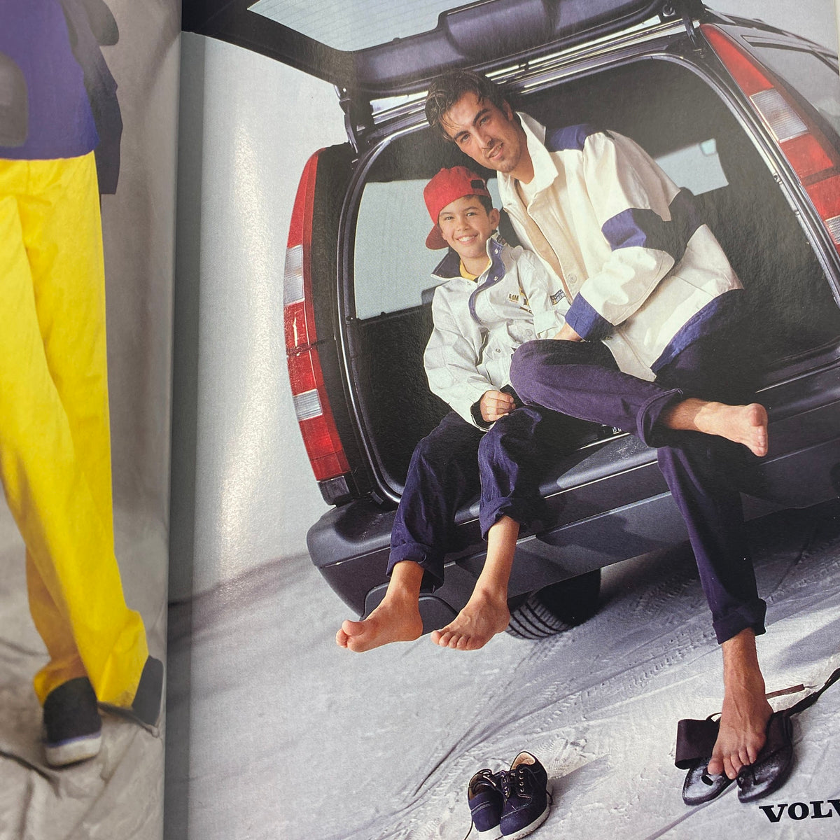 Fashion photo inside L'uomo Vogue Magazine March 1998 featuring a male model with a child in a car, showcasing casual wear.
