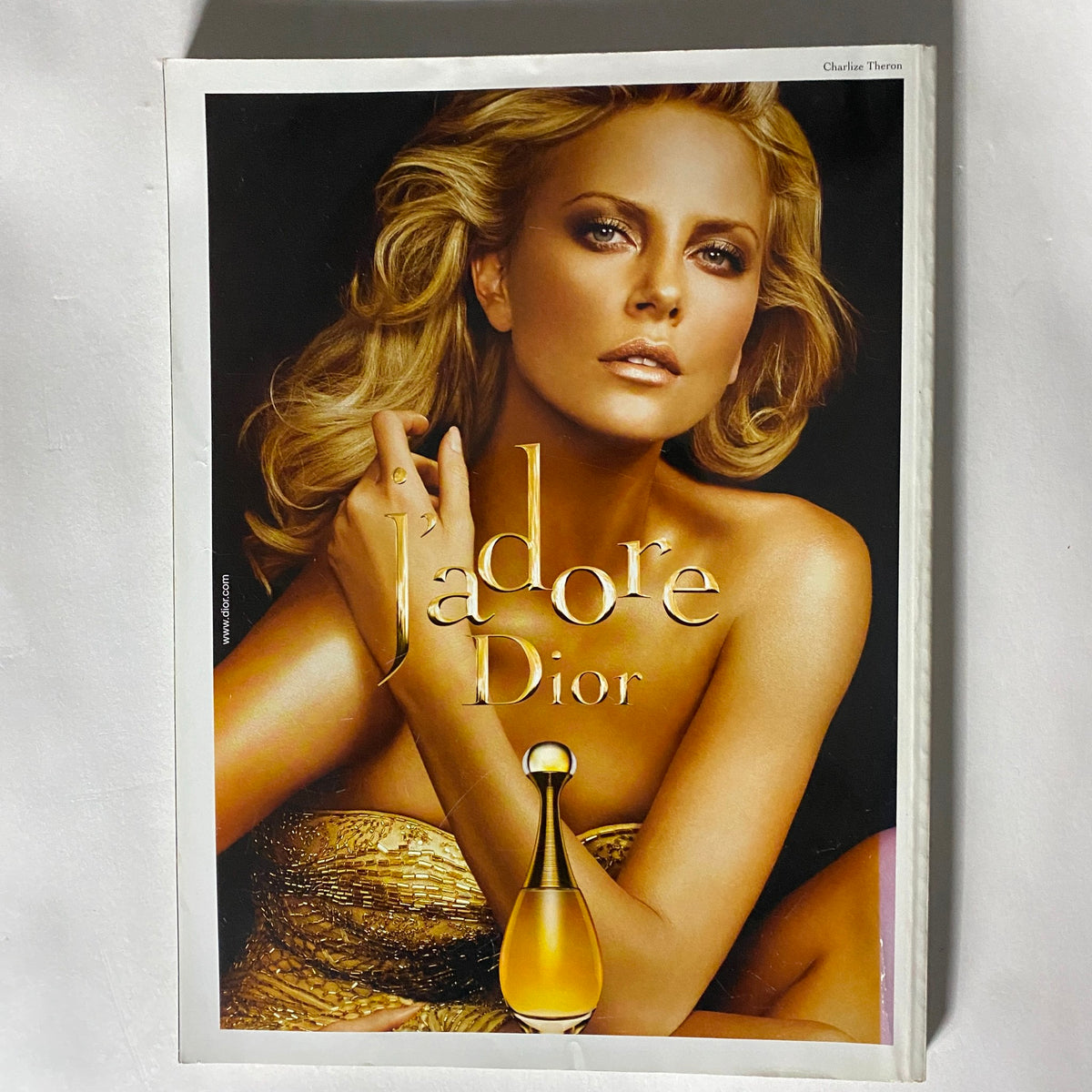 Cover image for the J'adore Dior advertisement featuring a glamorous woman with long blonde hair wearing a golden dress. The advertisement is a key highlight in Harper's Bazaar UK Magazine October 2009, emphasizing luxury and beauty.