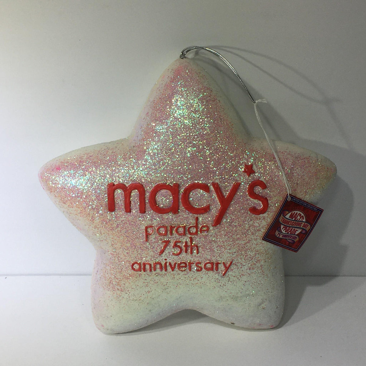 Macy's Thanksgiving Day Parade 75th Anniversary Collectible, featuring a sparkling star ornament with a glittery finish and the text 'macys parade 75th anniversary'.