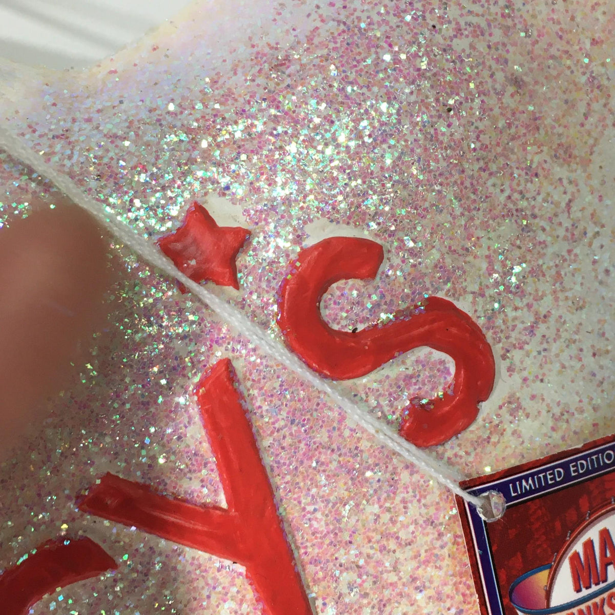 Close-up of the letter 's' on the Macy's Thanksgiving Day Parade 75th Anniversary Collectible star ornament, displaying the intricate details and sparkling glitter.