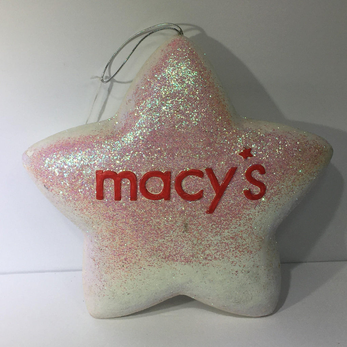 Macy's Thanksgiving Day Parade 75th Anniversary Collectible star ornament covered in glitter with a red 'macy's' logo.
