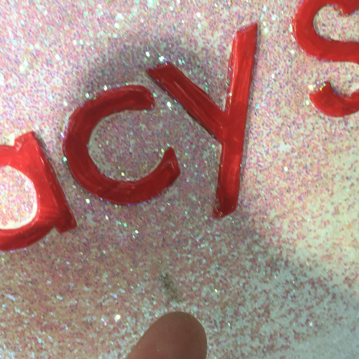 Close-up of glittery star ornament featuring the text 'macy's', highlighting the careful paintwork.