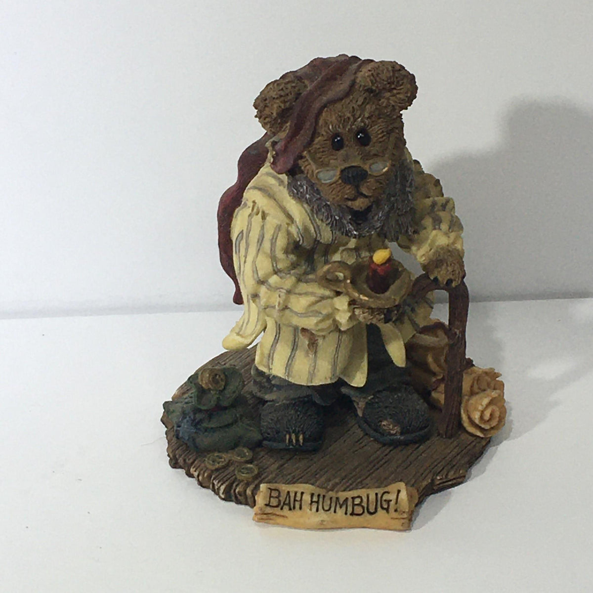The Bearstone Collection: Style #228333 PAW Scrooge McBear depicted as a bear in a nightgown holding a candle and walking stick, with a 'Bah Humbug!' sign, showcasing a whimsical holiday collectible.