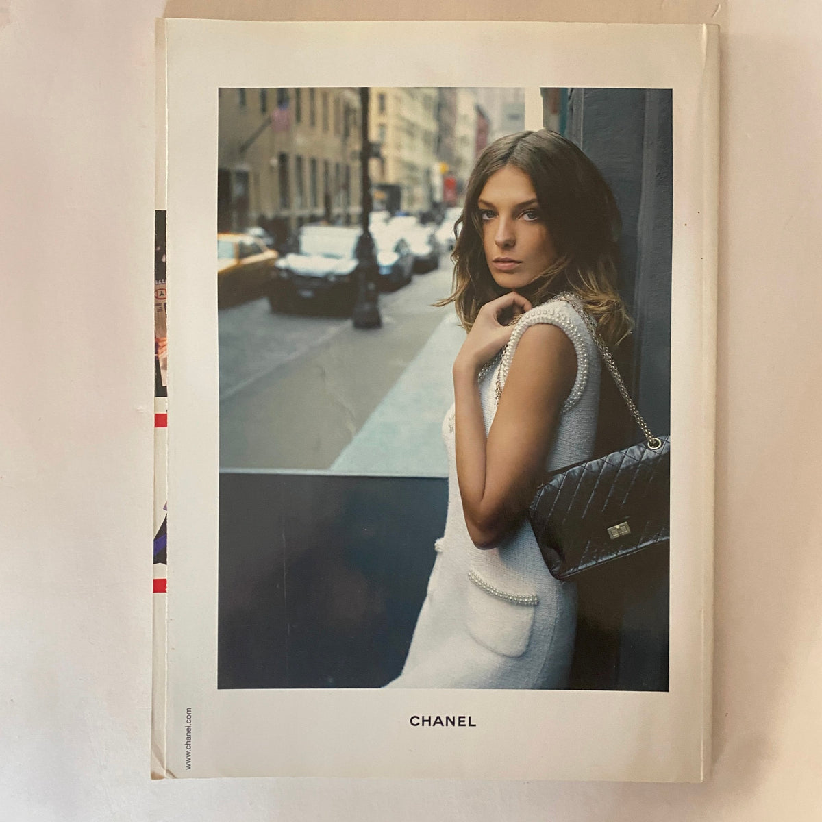 Harpers & Queen UK Magazine August 2005 page featuring a Chanel advertisement with a model posing in a stylish white outfit with a Chanel handbag, set against a city street backdrop.