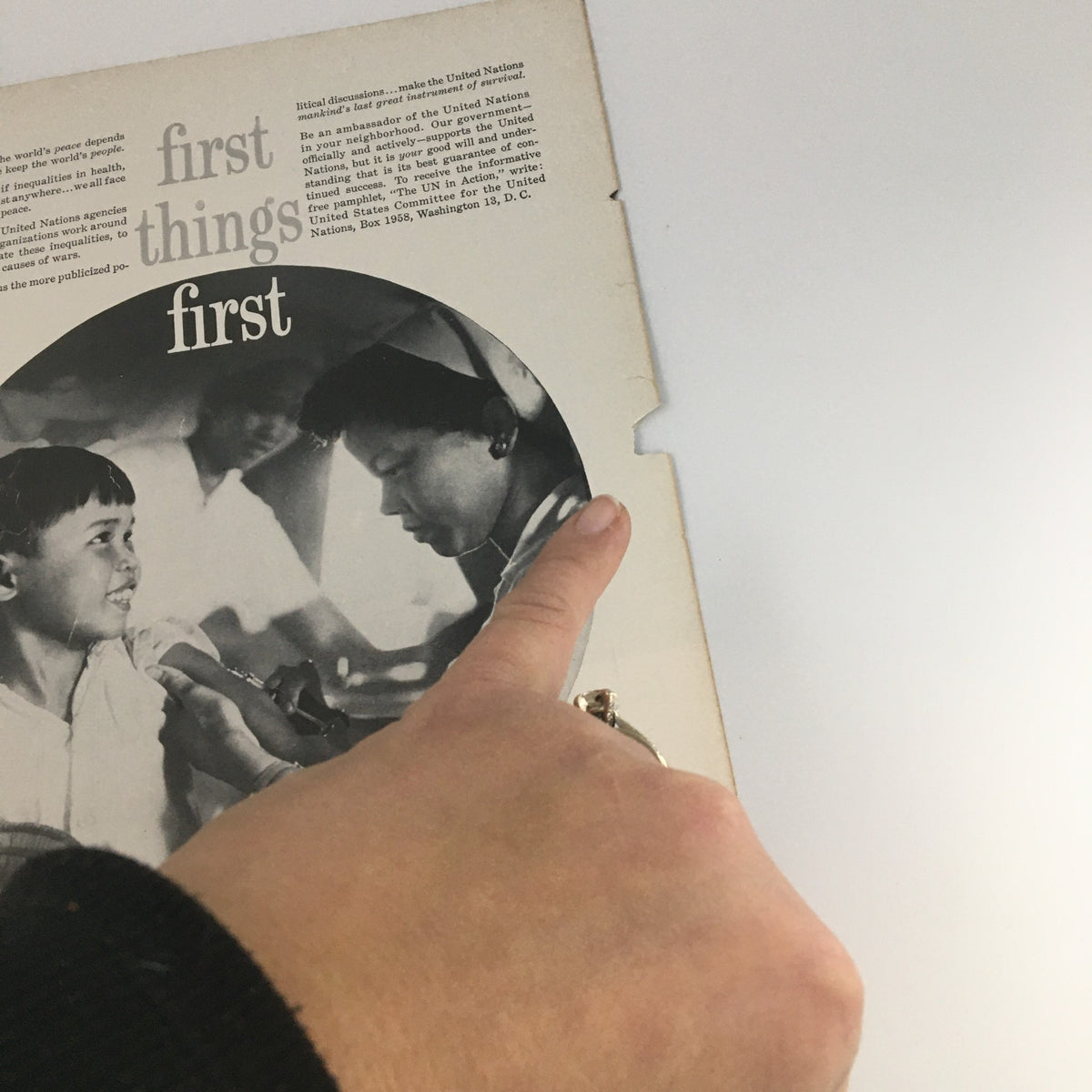 Close-up of hands pointing to a vintage magazine page, showcasing an illustration or photograph, part of the VTG Motion Picture Magazine April 1959 Dick Clark and Family Cover.