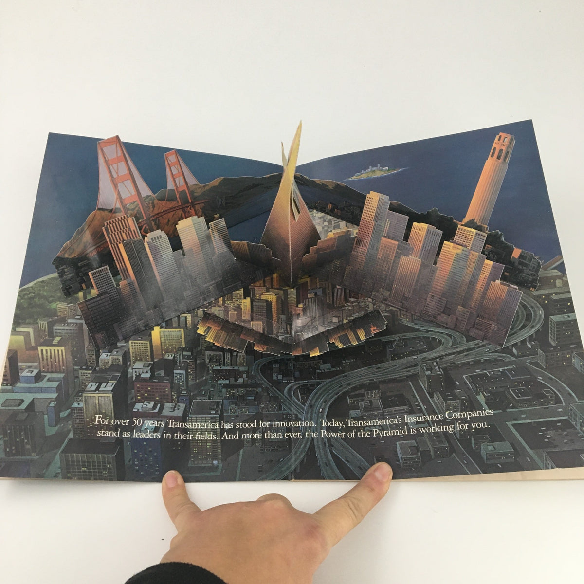 Folded open page from a magazine featuring a pop-up design illustrating the San Francisco skyline along with text about Transamerica Insurance Company.