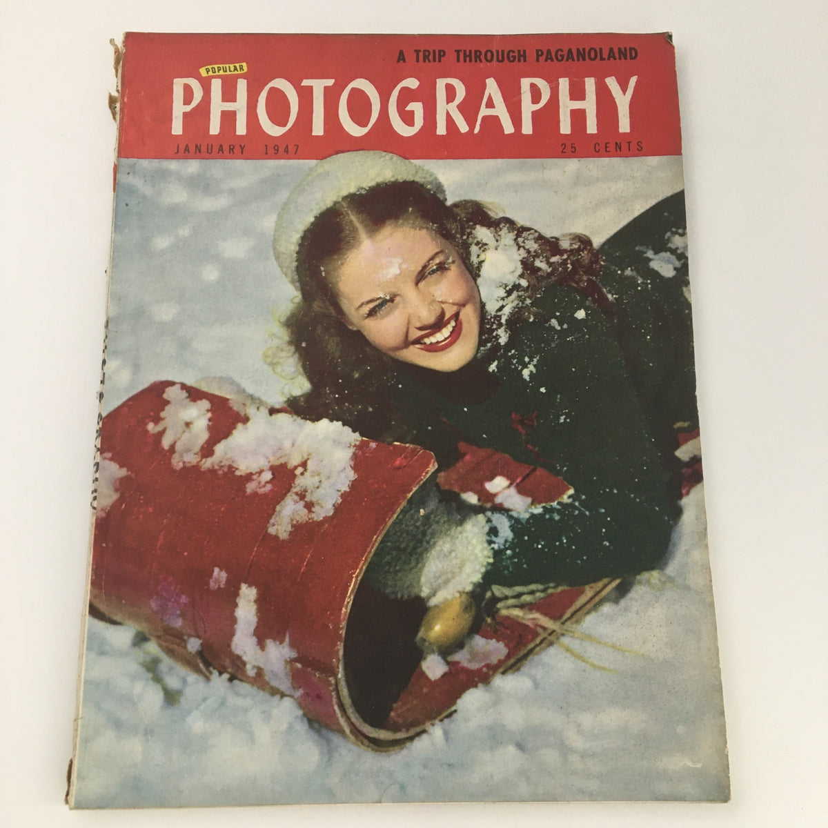 VTG Popular Photography Magazine January 1947 cover featuring a smiling woman in a snow scene with a vintage sled, highlighting the article 'A Trip Through Paganoland'.