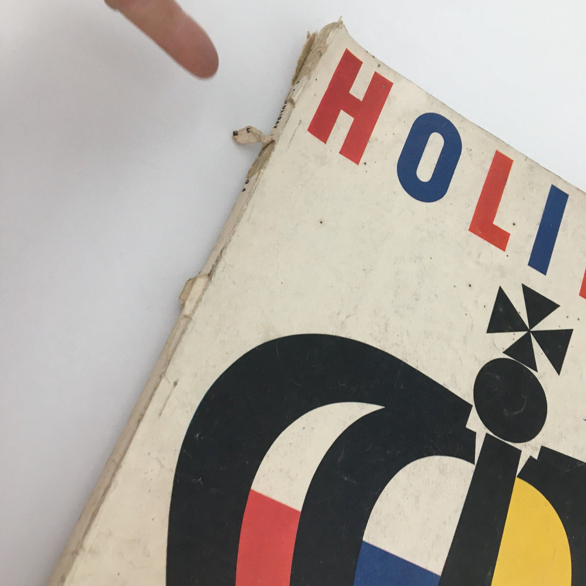 Close-up view of the VTG Holiday Magazine April 1958 showing the top edge with wear and a hand pointing at the damage, highlighting its vintage condition.