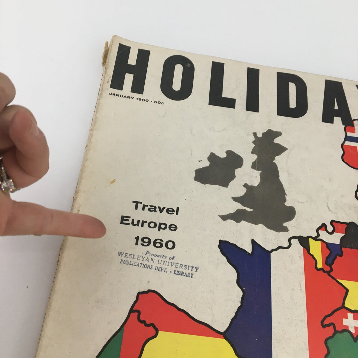 Close-up of the VTG Holiday Magazine January 1960 cover showing the title 'Holiday' and text 'Travel Europe 1960' with finger pointing to details.