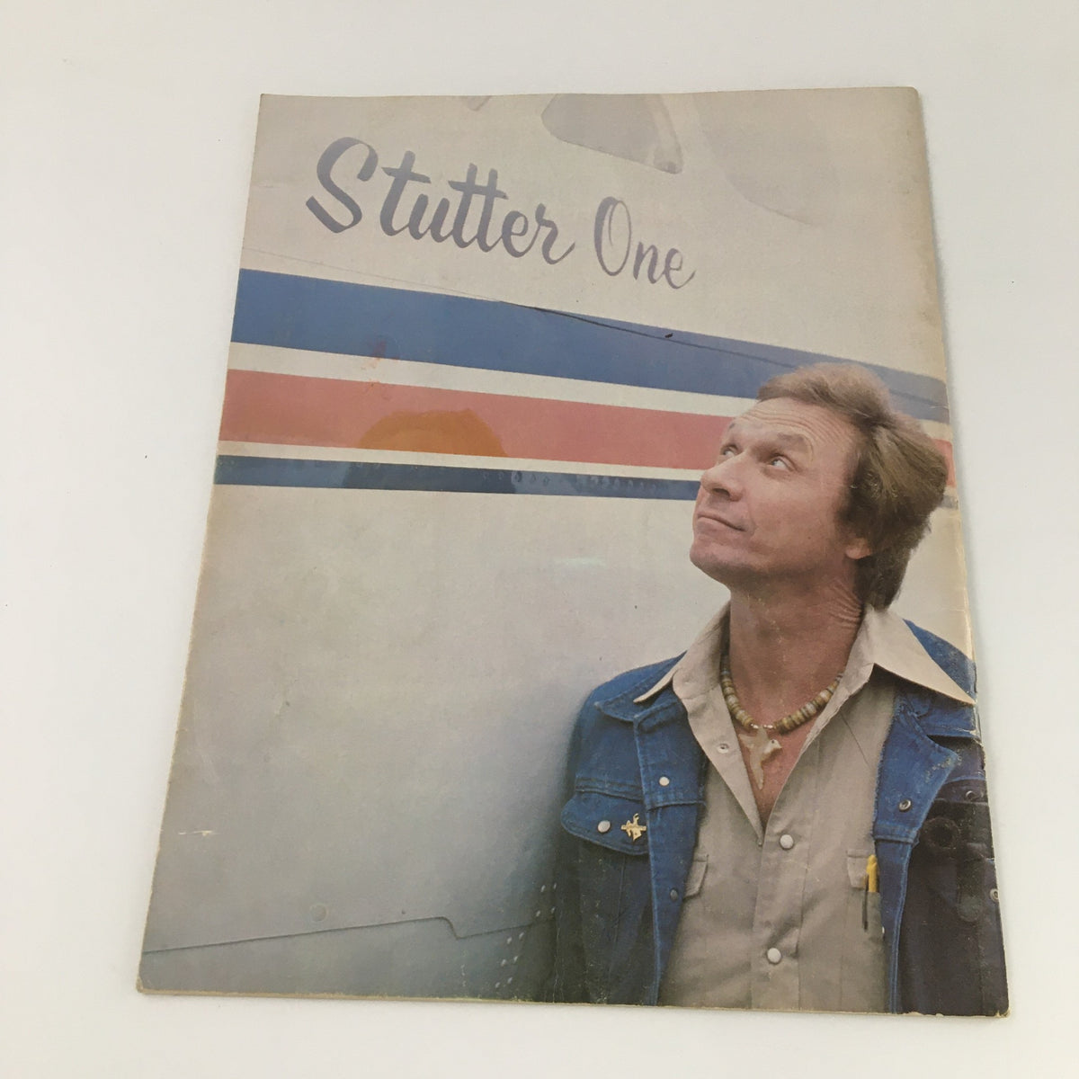 Cover of the VTG 1976 Mel Tillis Souvenir Program featuring Mel Tillis looking up with an airplane in the background, showcasing a nostalgic style of the era.