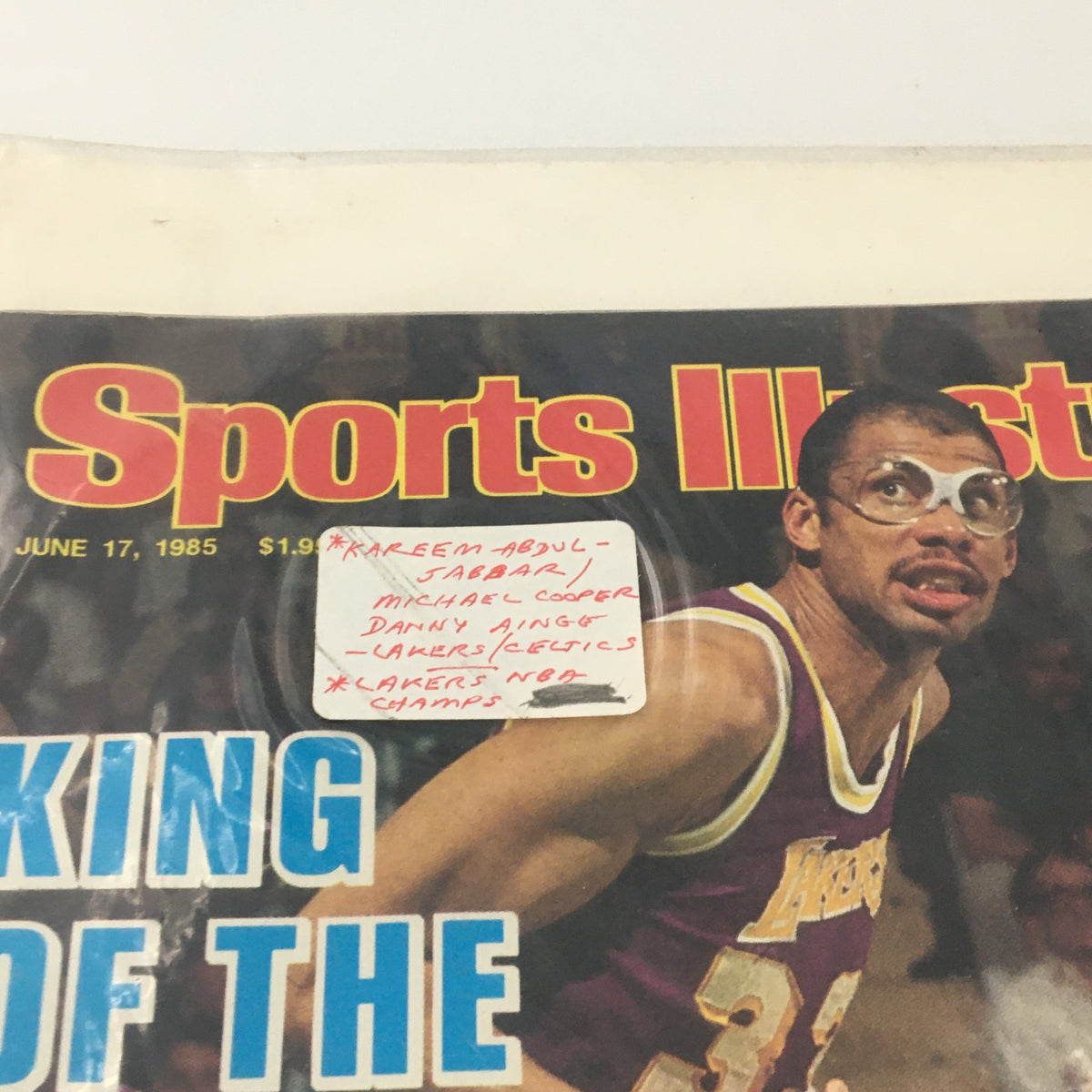 Close-up of Sports Illustrated Magazine June 17, 1985 cover stating names Kareem Abdul-Jabbar and Michael Cooper with the label 'Lakers NBA Champs'.
