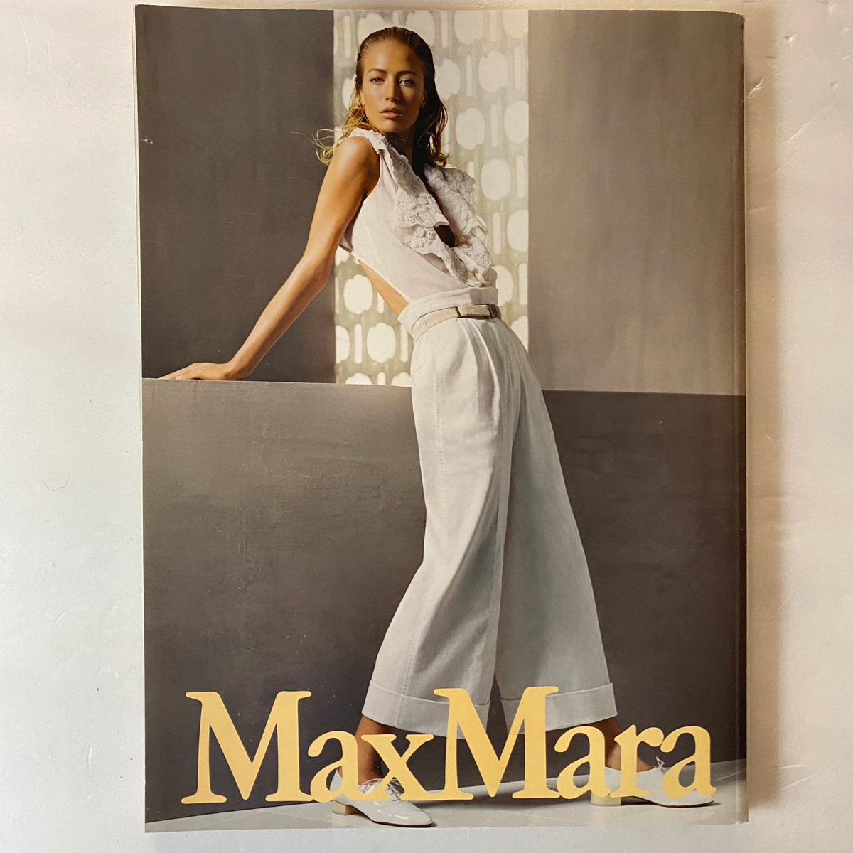 Model in a stylish outfit posing against a geometric background in MaxMara, featured in Harper's Bazaar UK Magazine April 2006 Flávia de Oliveira Cover. Elegant fashion showcasing timeless design.