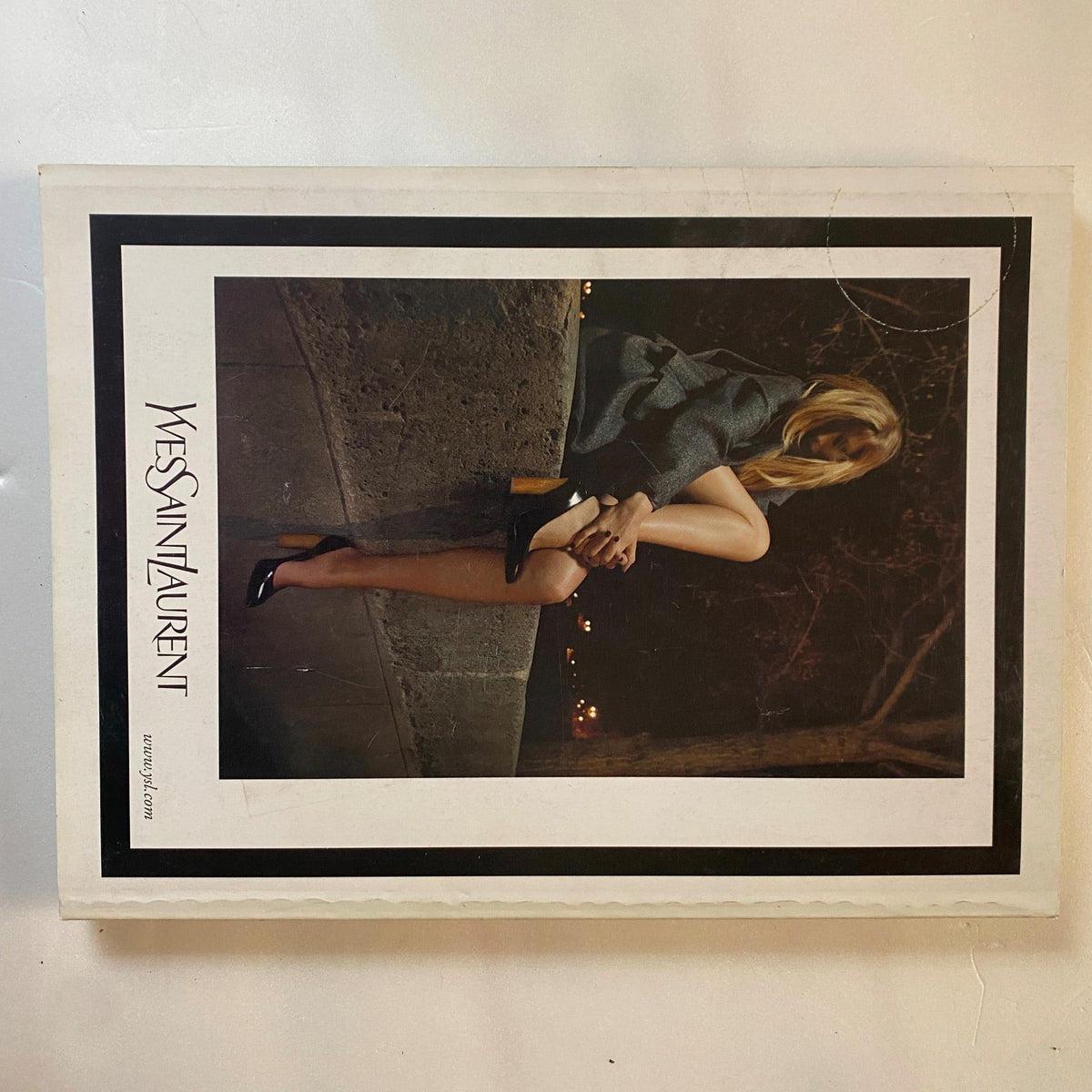 Yves Saint Laurent advertisement from Elle Magazine October 2007 featuring a stylish model dressed in formal attire, sitting against a dark urban backdrop. This image represents luxury fashion and personal style trends of the late 2000s.