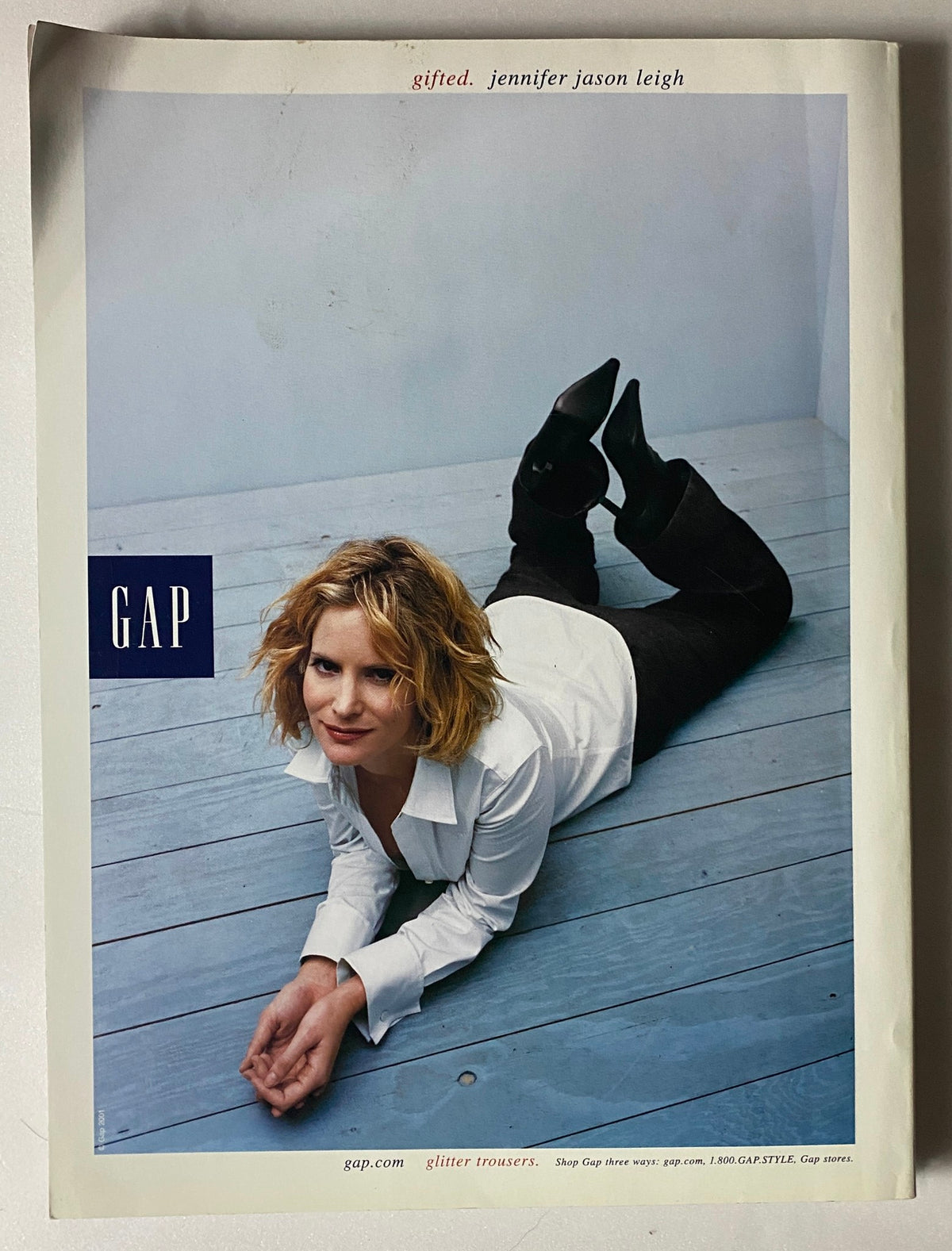 Gap advertisement featuring actress Jennifer Jason Leigh posing on her stomach in casual attire, embodying the fashion trends of the early 2000s.