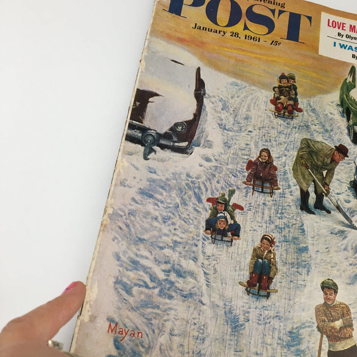 Close-up of the cover of The Saturday Evening Post from January 28, 1961, highlighting a snowy scene with children on sleds and an adult clearing snow, reflecting vintage American culture.