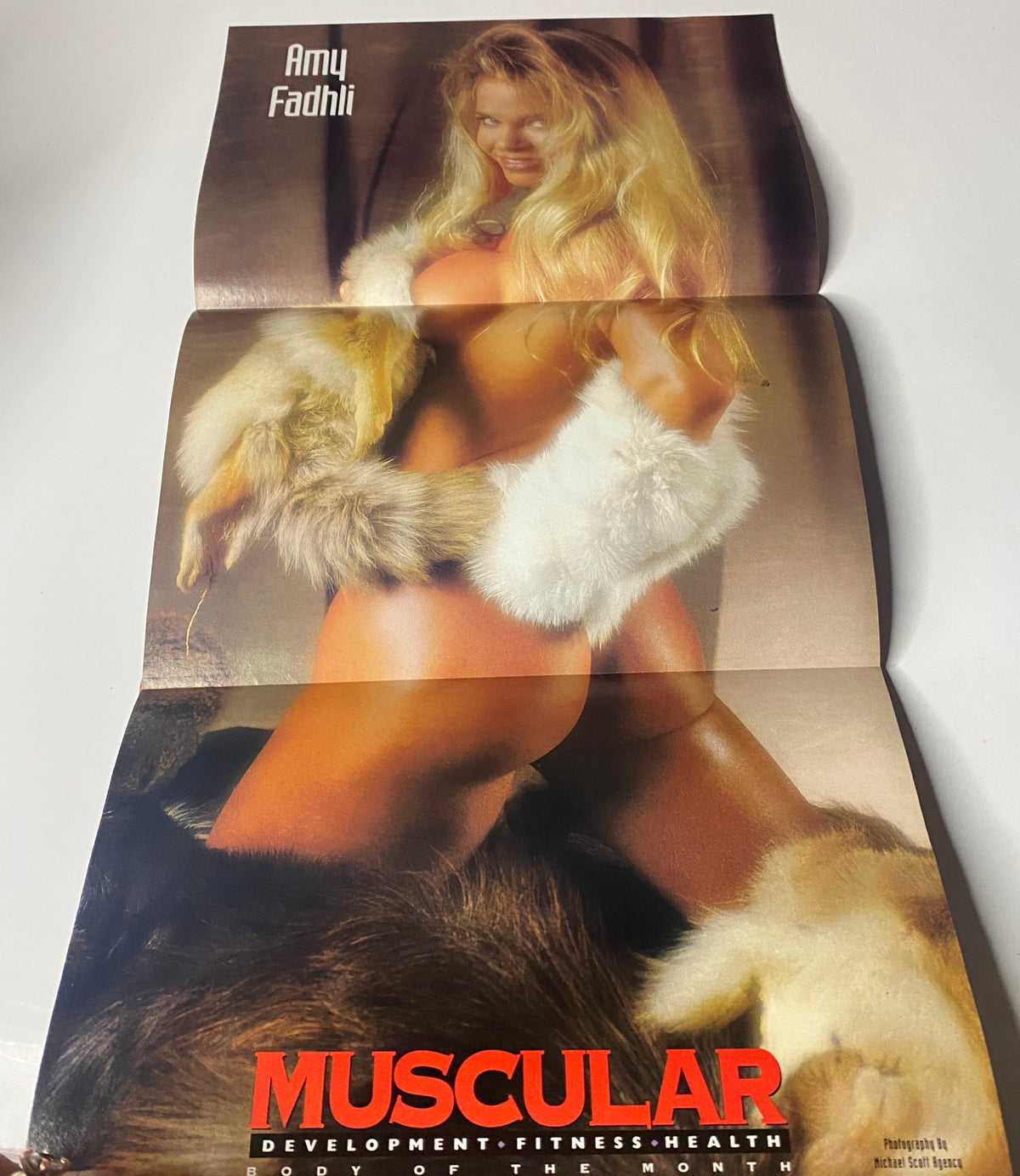 Muscular Development Magazine January 1996 featuring Amy Fadhli in a provocative pose with fur accents, showcasing strength and beauty. This image is part of the magazine's fold-out poster.