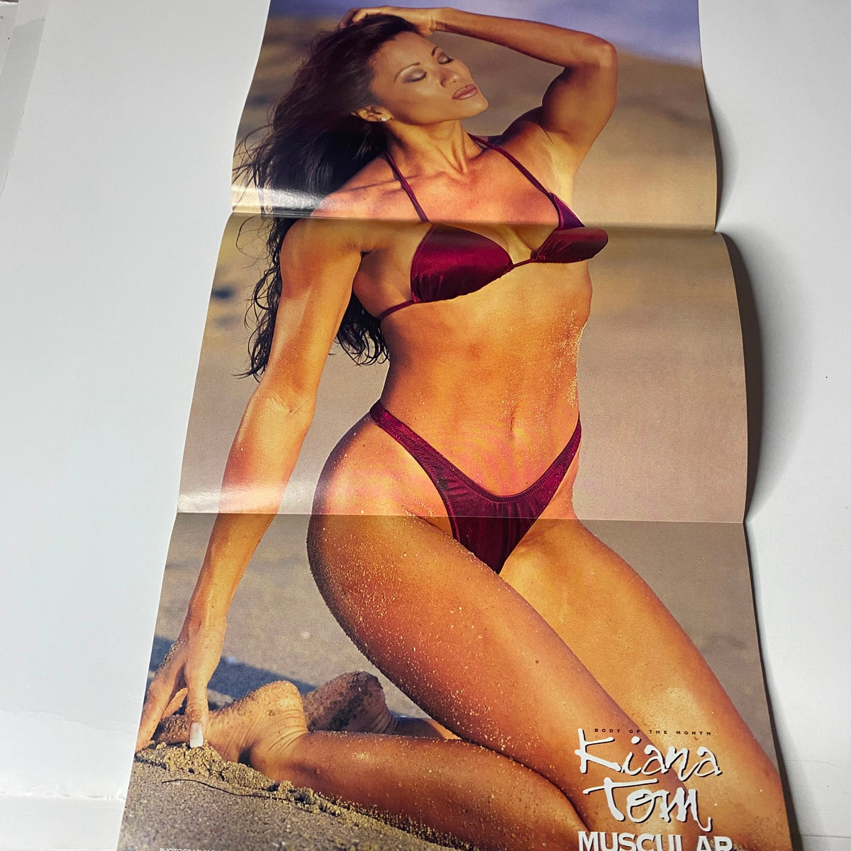 Fold-out poster from Muscular Development Magazine July 1996 showcasing Kiana Tom in a beach setting, embodying athletic beauty and fitness inspiration.