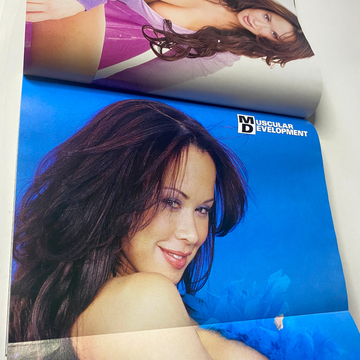Pictorial spread from Muscular Development Magazine May 2001 featuring Noreyma against a vibrant blue background. Highlights the magazine's emphasis on fitness and body aesthetics.