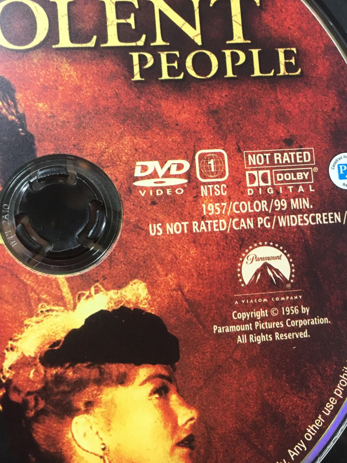 Close-up of the Three Violent People 2005 DVD disc showing the title, format details, and vintage logo of Paramount Pictures.