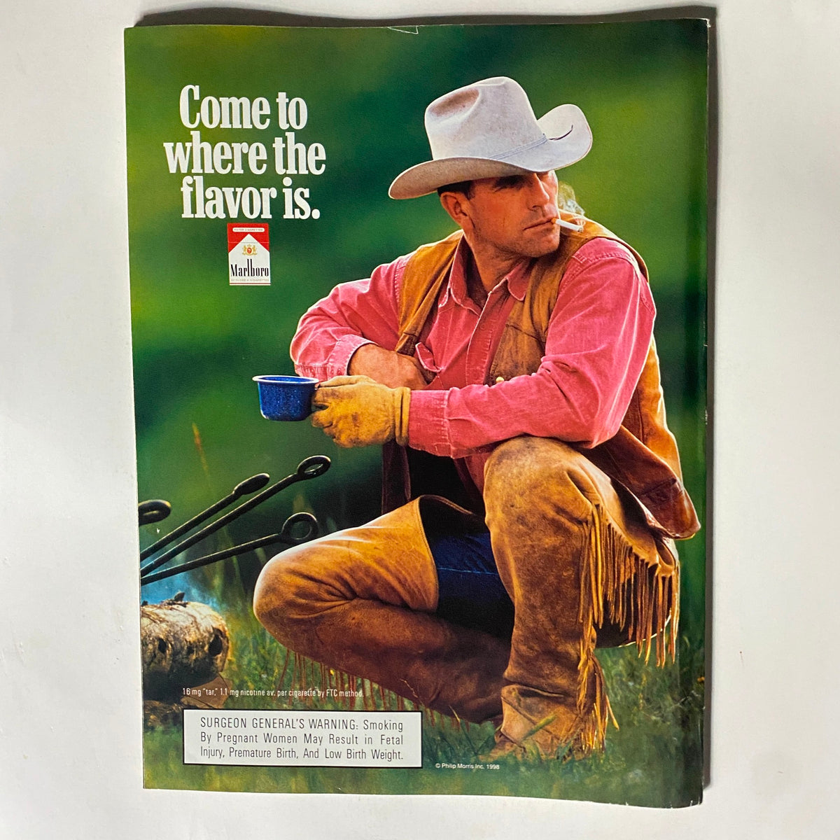 Advertisement from the George Magazine July 1998 issue featuring a cowboy image with the slogan 'Come to where the flavor is.' promoting Marlboro cigarettes.