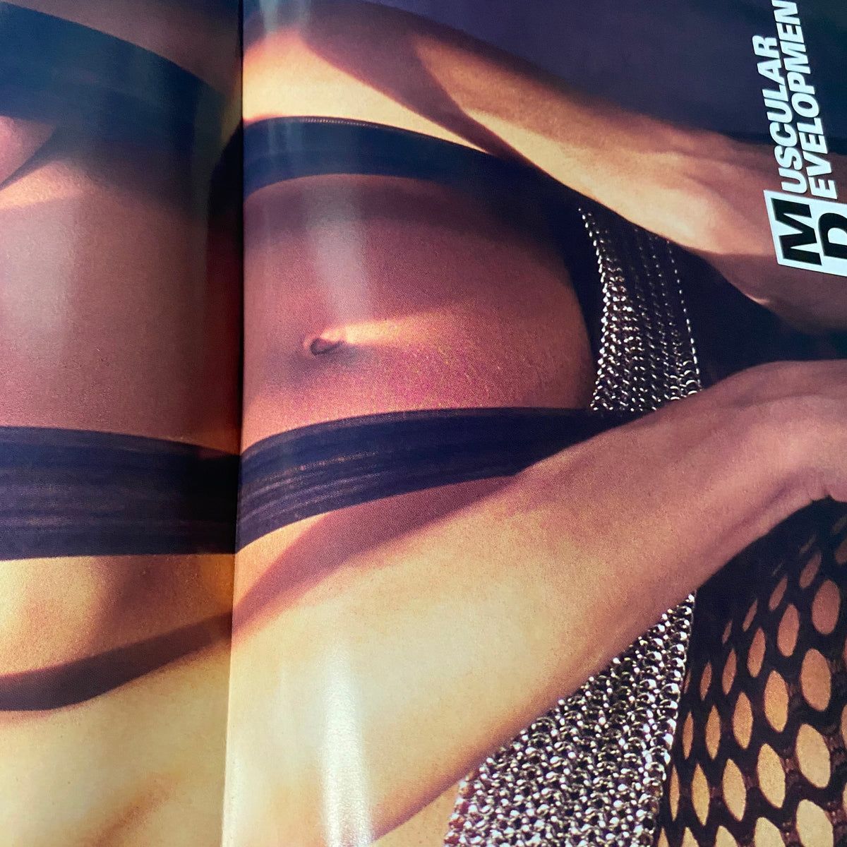 Artistic shot from Muscular Development Magazine May 2003 capturing a model in a dynamic pose, emphasizing fitness aesthetics and style, part of the magazine's exclusive content.