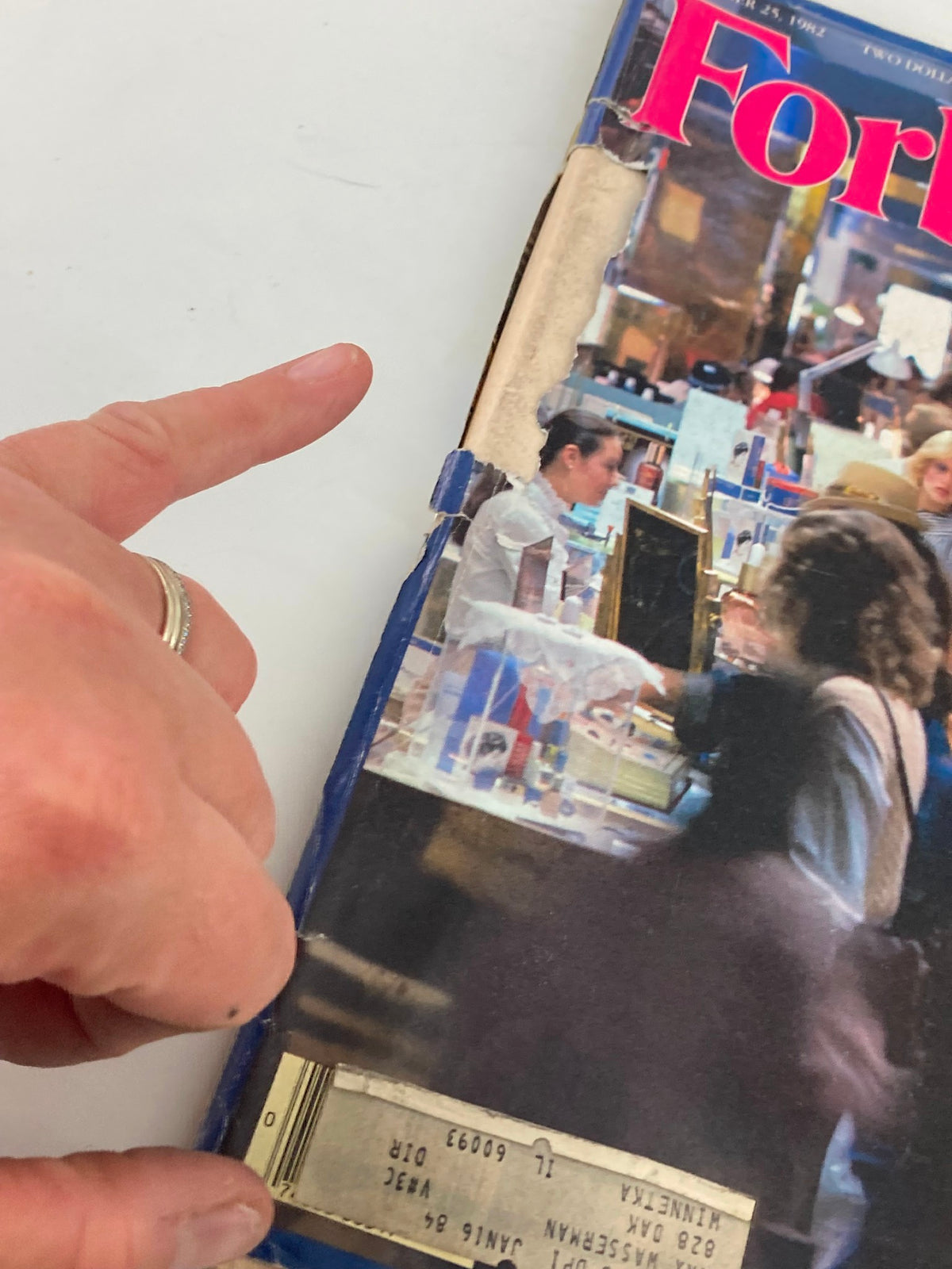 Close-up of the damaged edge of the Forbes Magazine cover from October 25, 1982, showcasing 'The Cosmetics Game Today,' with emphasis on the visible wear and address label.
