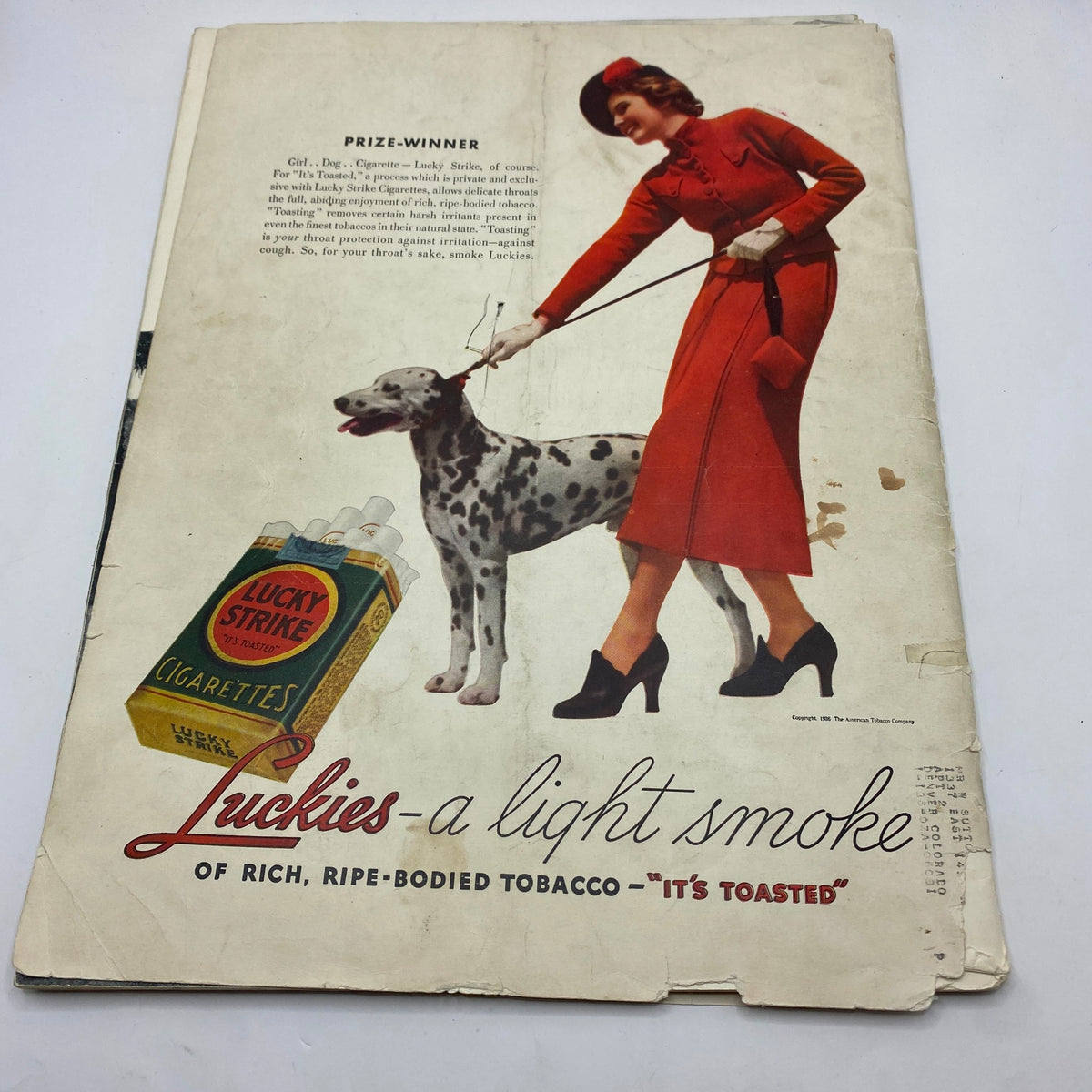 Back cover of VTG Life Magazine November 23, 1936, showcasing a vintage advertisement for Lucky Strike cigarettes, featuring a woman in a red dress with her dog. An example of 1930s advertising culture.