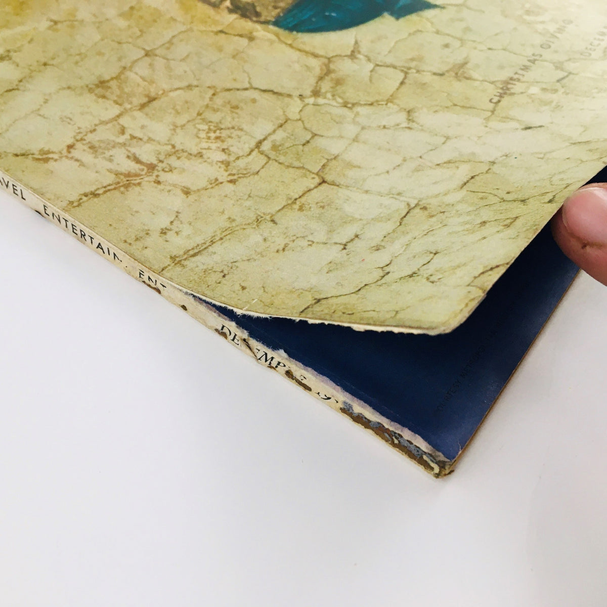 Close-up view of the VTG Flair Magazine December 1950 cover showing wear and a finger holding the page, highlighting the vintage condition and character of the Christmas edition.