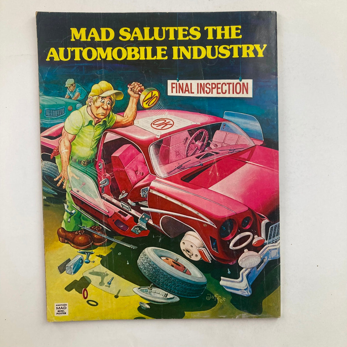 Cover of Mad Salutes the Automobile Industry, featuring a comedic illustration of a mechanic inspecting a red car surrounded by auto parts, with a humorous caption 'FINAL INSPECTION'.