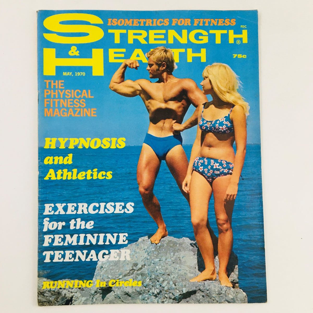 Strength & Health Magazine May 1970 cover featuring a muscular man posing and a woman in a bikini by the sea, highlighting fitness and health topics of the era.