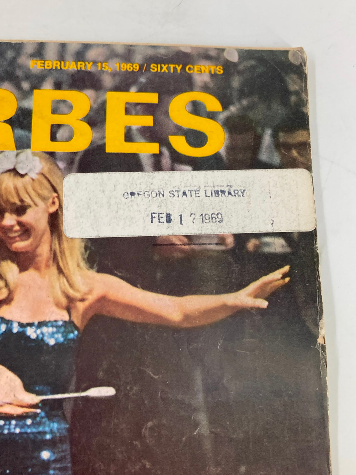 Detail of the vintage Forbes Magazine cover dated February 15, 1969, featuring the magazine's title and library stamp, emphasizing the 'Multi-Billion-Dollar American Ritual' theme.