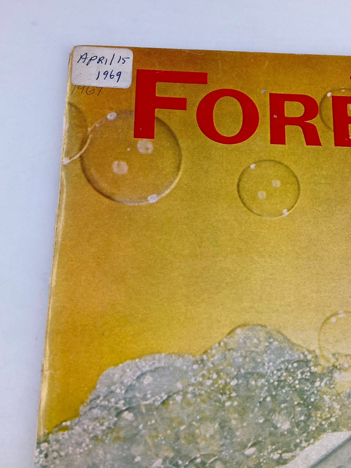 Close-up of the cover of the vintage Forbes Magazine April 15, 1969, highlighting the title 'Unsinkable?' related to Procter & Gamble, with decorative bubbles.