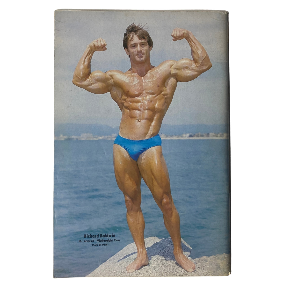 Back cover of IronMan Magazine January 1981 Vol 40 No. 2 featuring Richard Baldwin, Mr. America Middleweight Class, flexing his muscles by the ocean.
