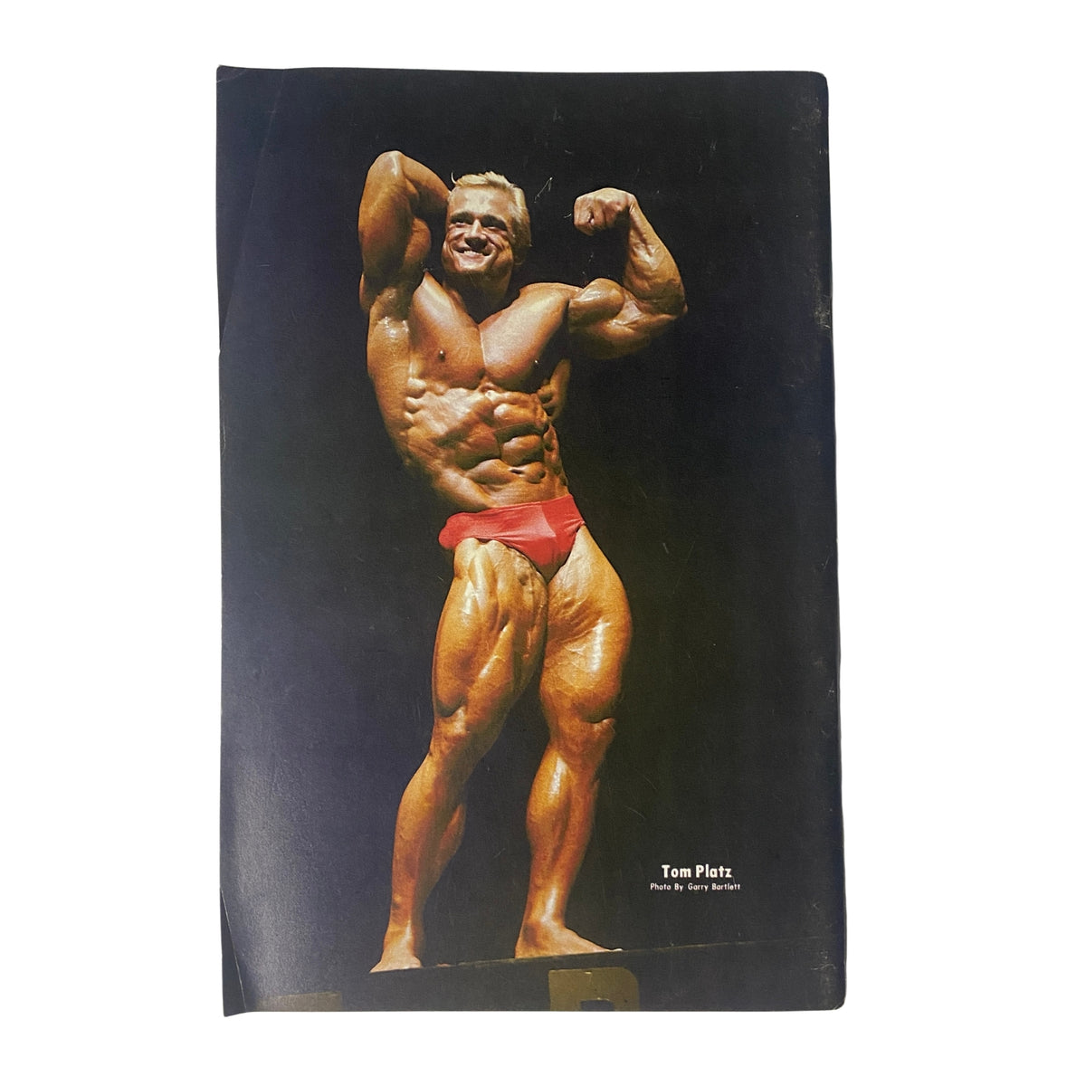 Back cover of IronMan Magazine May 1982 Vol 41 No. 4 featuring Tom Platz in a muscular pose, captured by photographer Garry Bartlett.