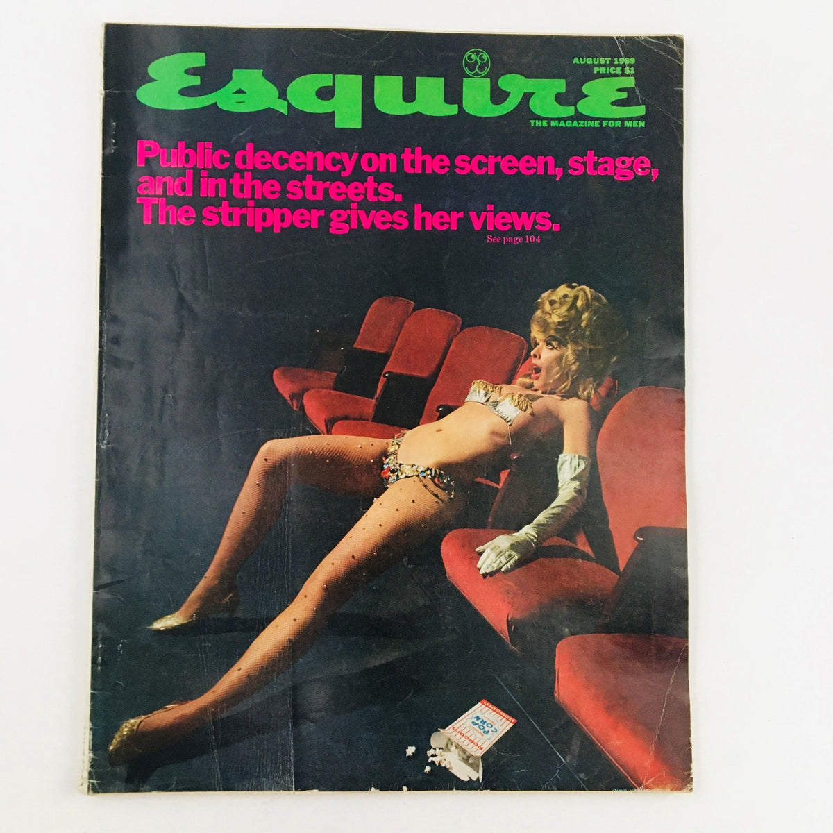 Cover of the VTG Esquire Magazine August 1969 issue featuring the title 'Public Decency On The Screen, Stage, and in the Streets. The Stripper Gives Her Views.' The cover art showcases a glamorous woman in a revealing outfit seated in a red theater chair, symbolizing the cultural dialogues of the late 1960s.